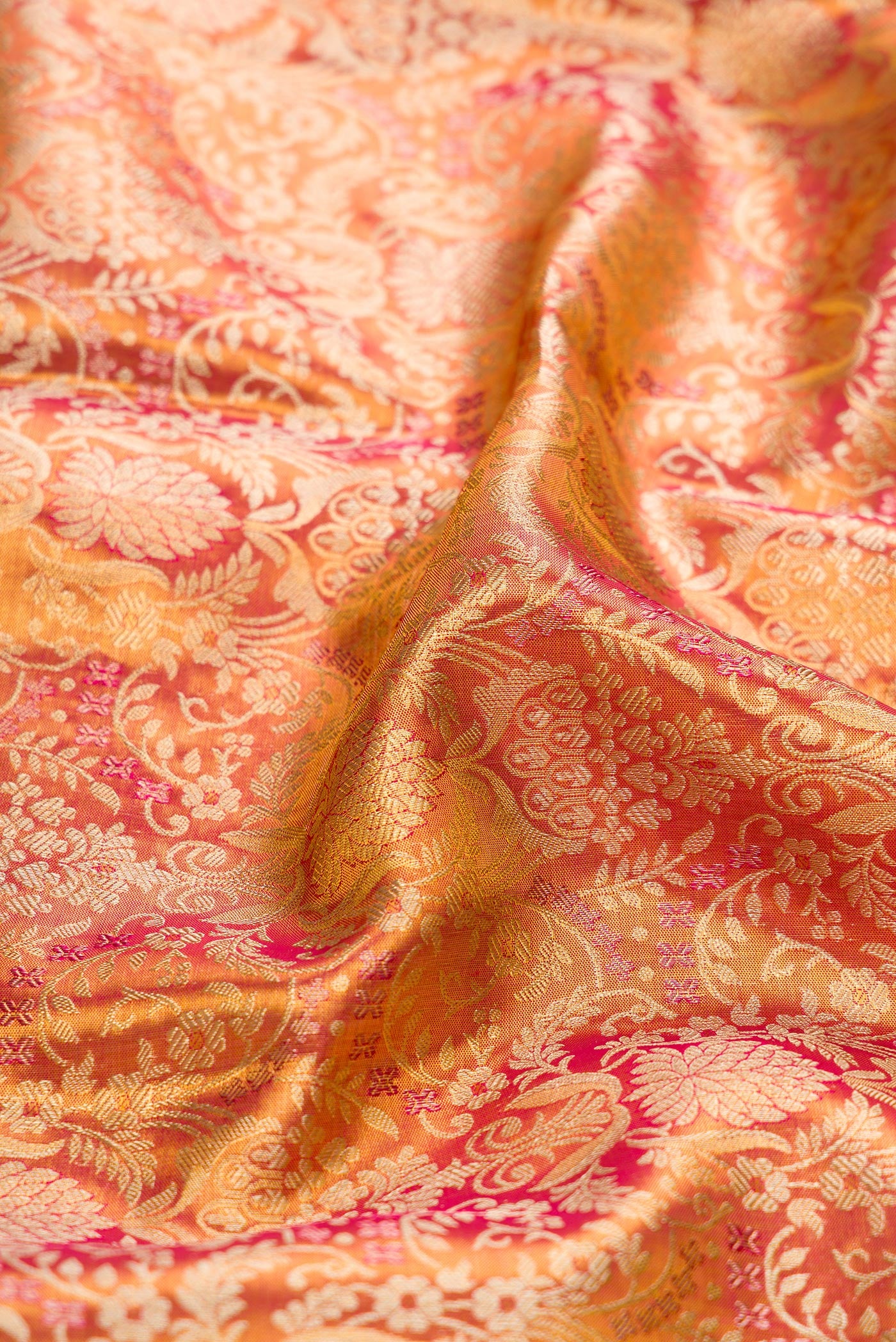 Close up of Coral Dual Tone Kanjivaram Tissue Silk Saree with Zari Brocade on the body and Fancy Border.  displaying folds