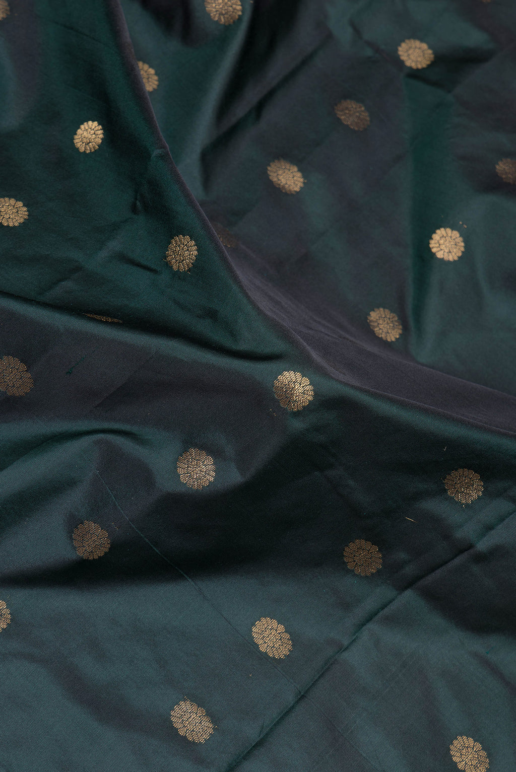 Close up of Bottle Green Paithani Silk Saree with Zari Butta on the body and Zari Border.  displaying folds