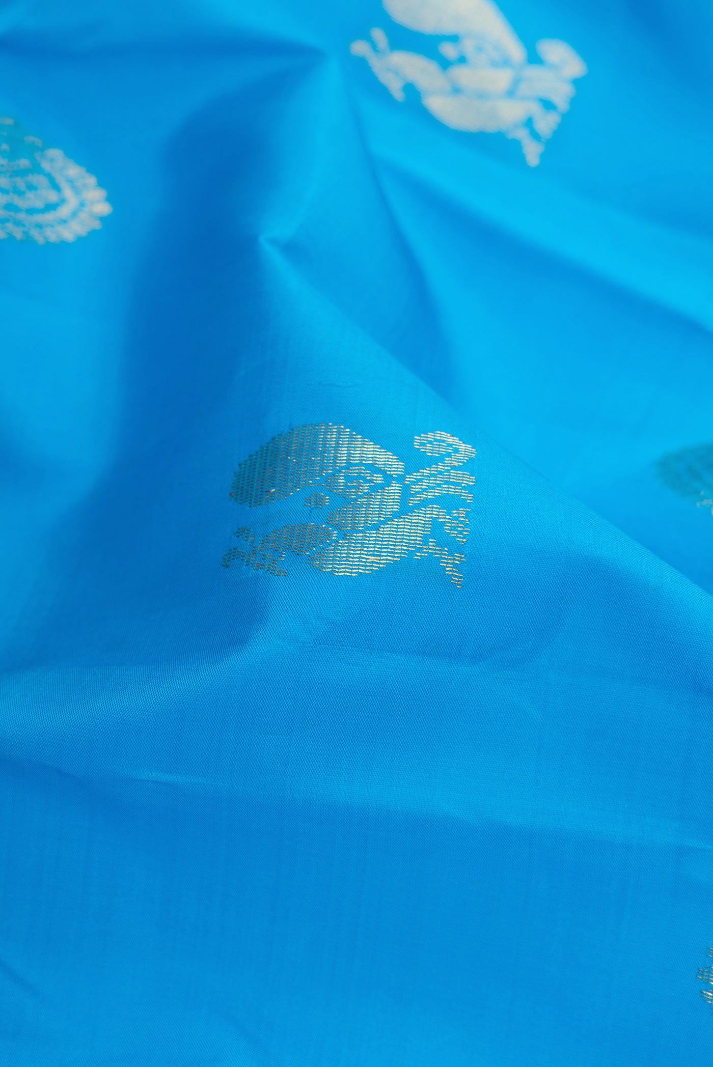 Close up of Sky Blue Kanchipuram Silk Saree with Zari Butta on the body and Fancy Border.  displaying folds