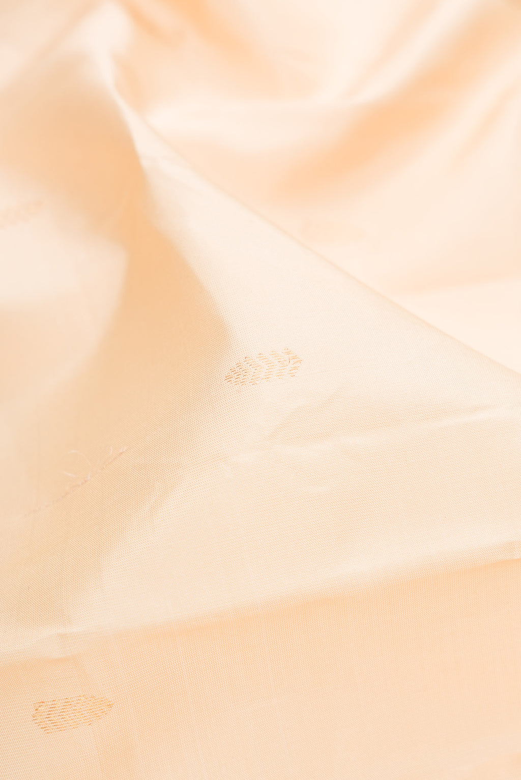 Close up of Cream Kanchipuram Silk Saree with Zari Butta on the body and Without Border.  displaying folds