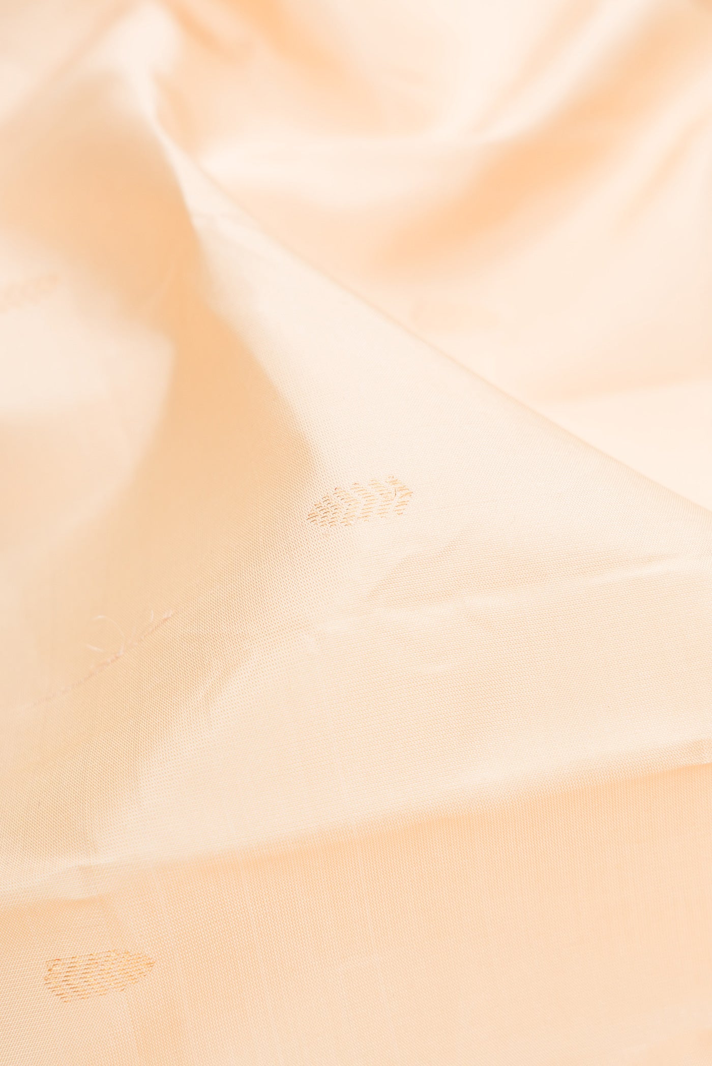 Close up of Cream Kanchipuram Silk Saree with Zari Butta on the body and Without Border.  displaying folds