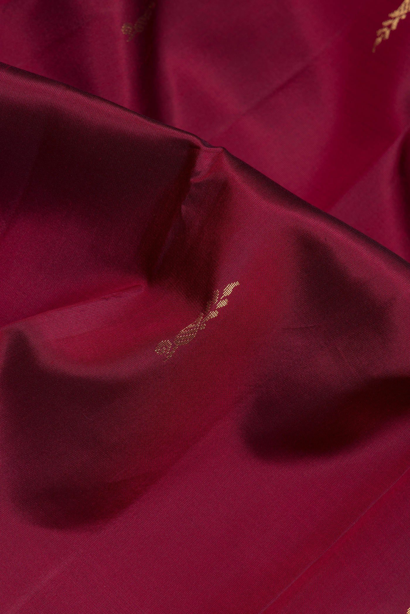 Close up of Maroon Dual Tone Blended Kanjivaram Silk Saree with Zari Butta on the body and Zari Border.  displaying folds
