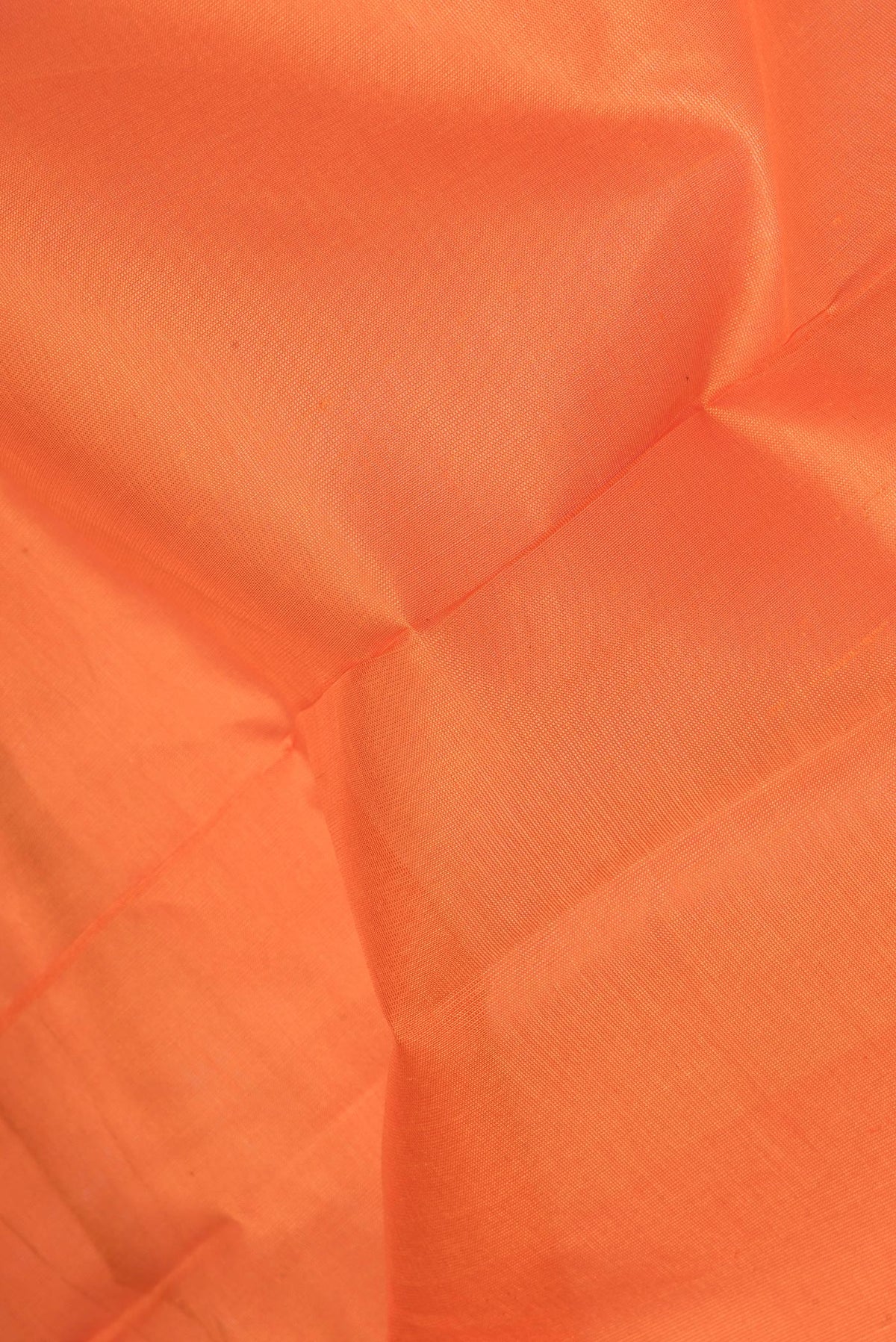 Close up of Orange Silk Cotton Saree with Plain Body and Zari Border.  displaying folds