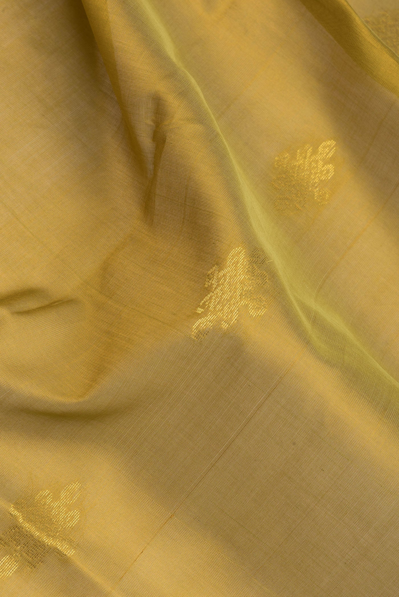 Close up of Mehandi Green Silk Cotton Saree with Zari Butta on the body and Zari Border.  displaying folds