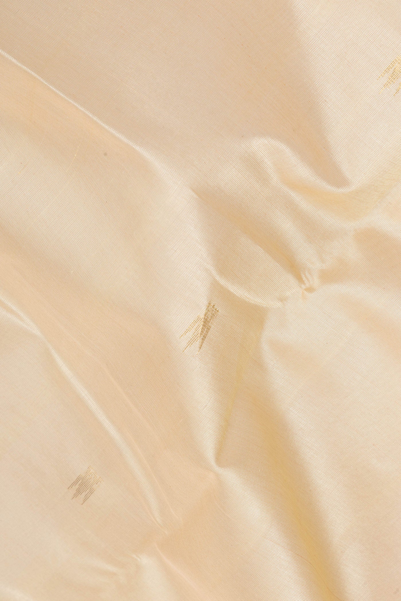 Close up of Beige Silk Cotton Saree with Zari Butta on the body and Zari Border.  displaying folds