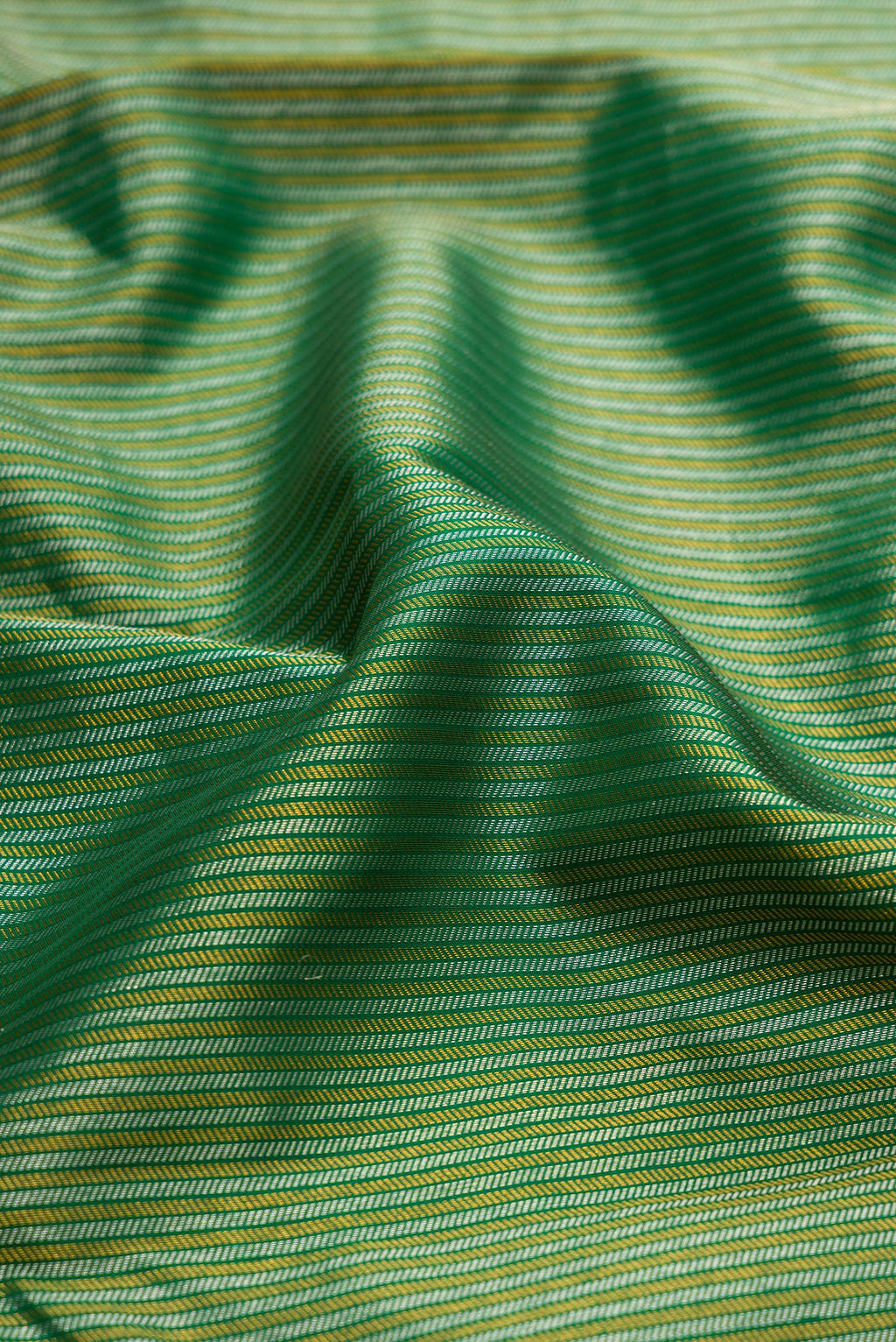 Close up of Bottle Green Kanchipuram Silk Saree with Zari Brocade on the body and Zari Border.  displaying folds