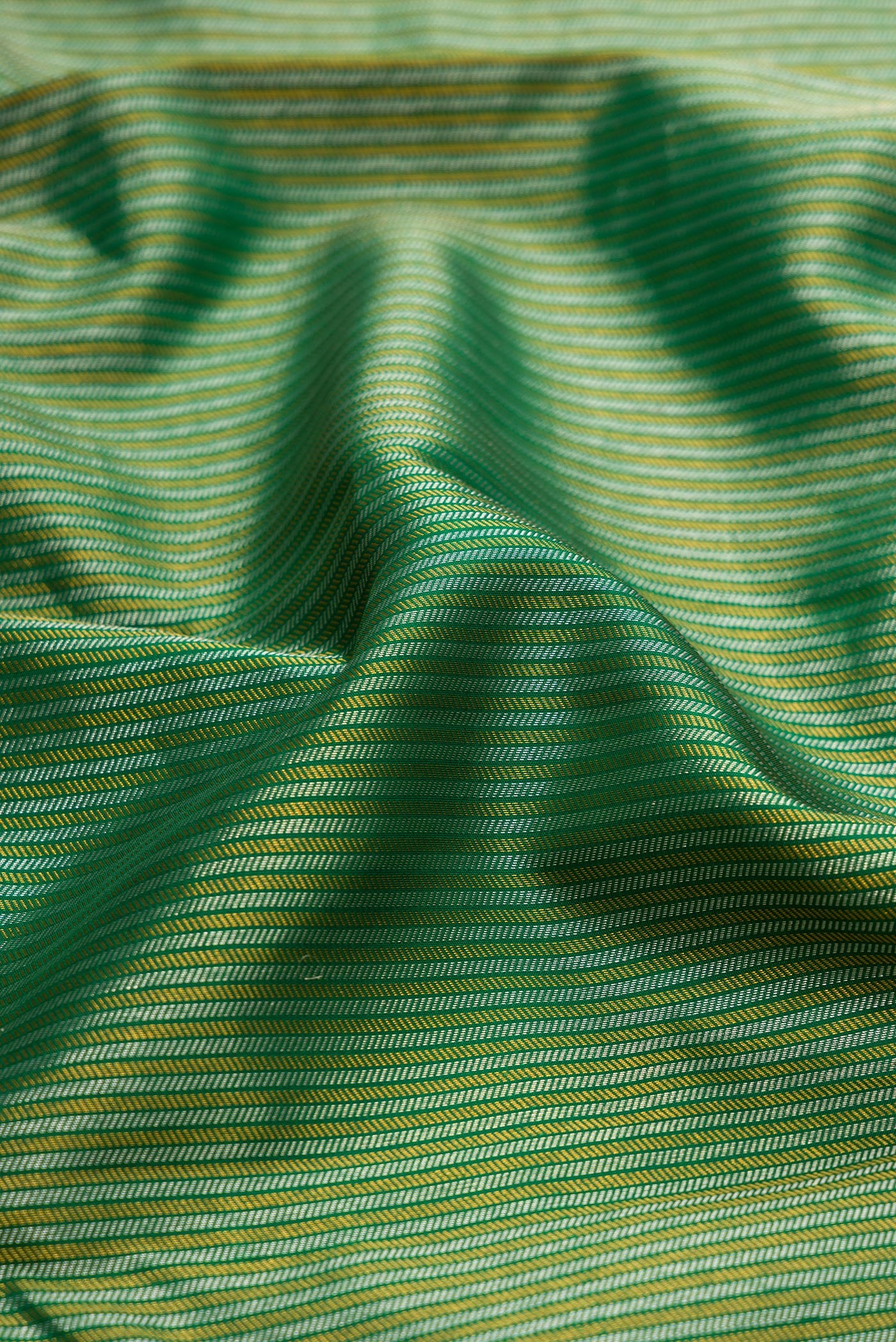 Close up of Bottle Green Kanchipuram Silk Saree with Zari Brocade on the body and Zari Border.  displaying folds