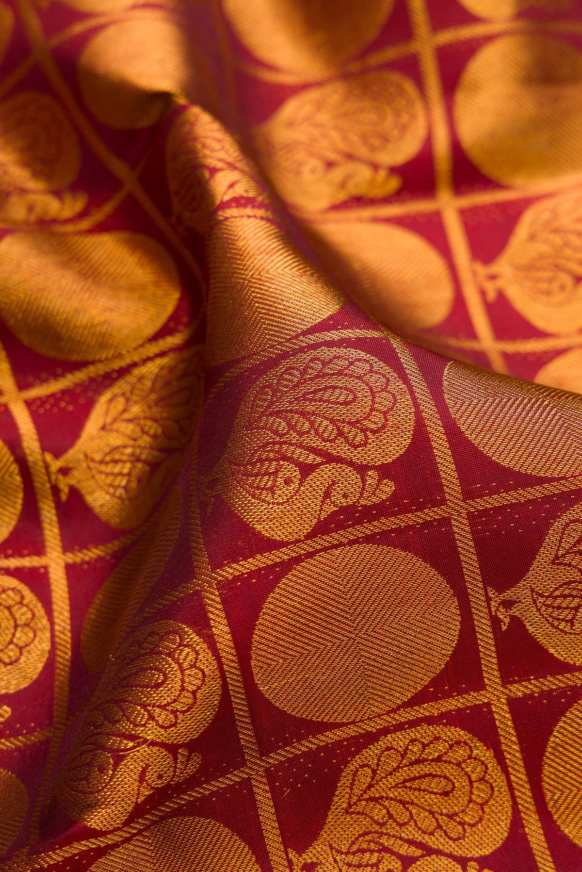 Close up of Maroon Kanchipuram Silk Saree with Zari Brocade on the body and Zari Border.  displaying folds