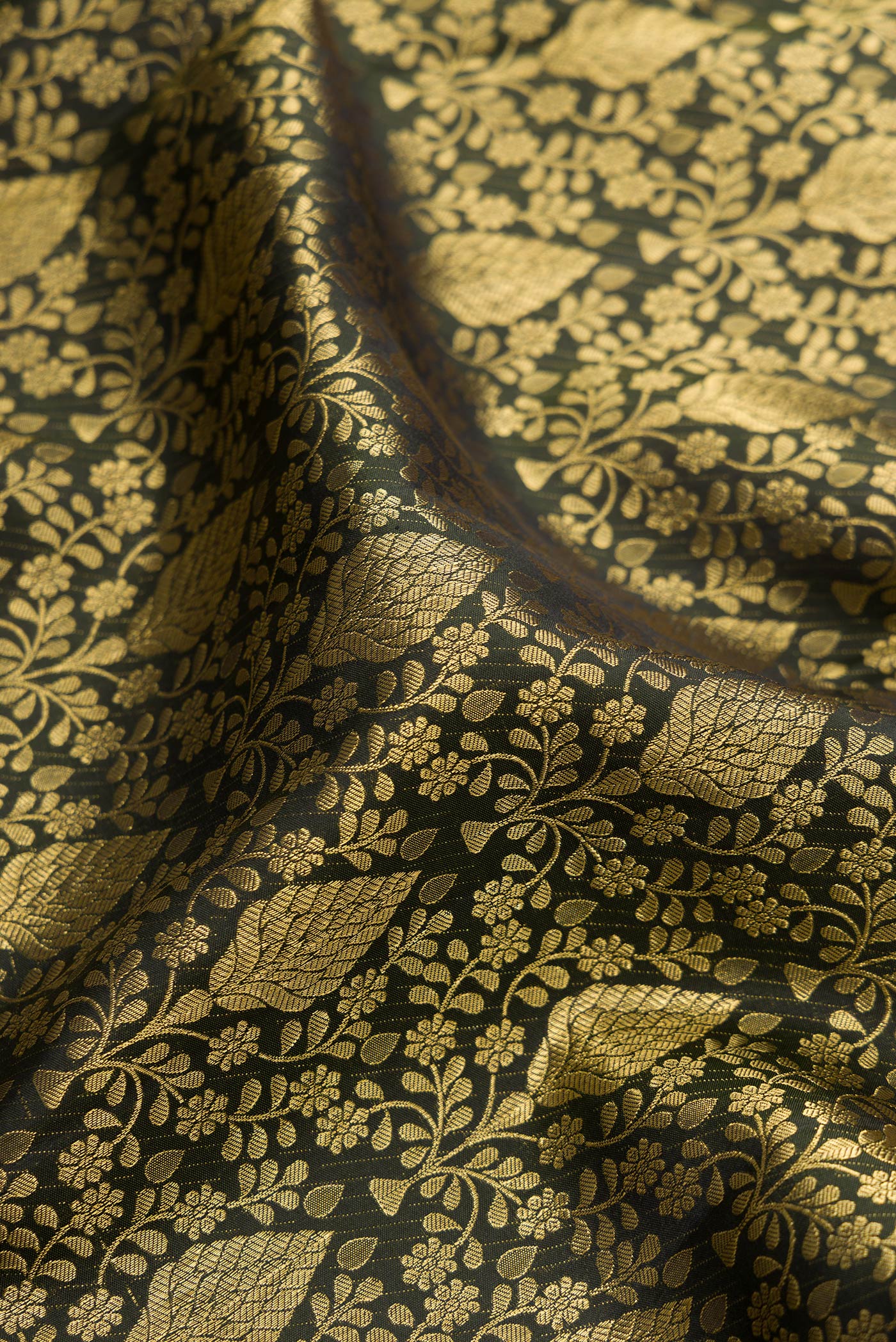 Close up of Bottle Green Kanchipuram Silk Saree with Zari Brocade on the body and Zari Border.  displaying folds