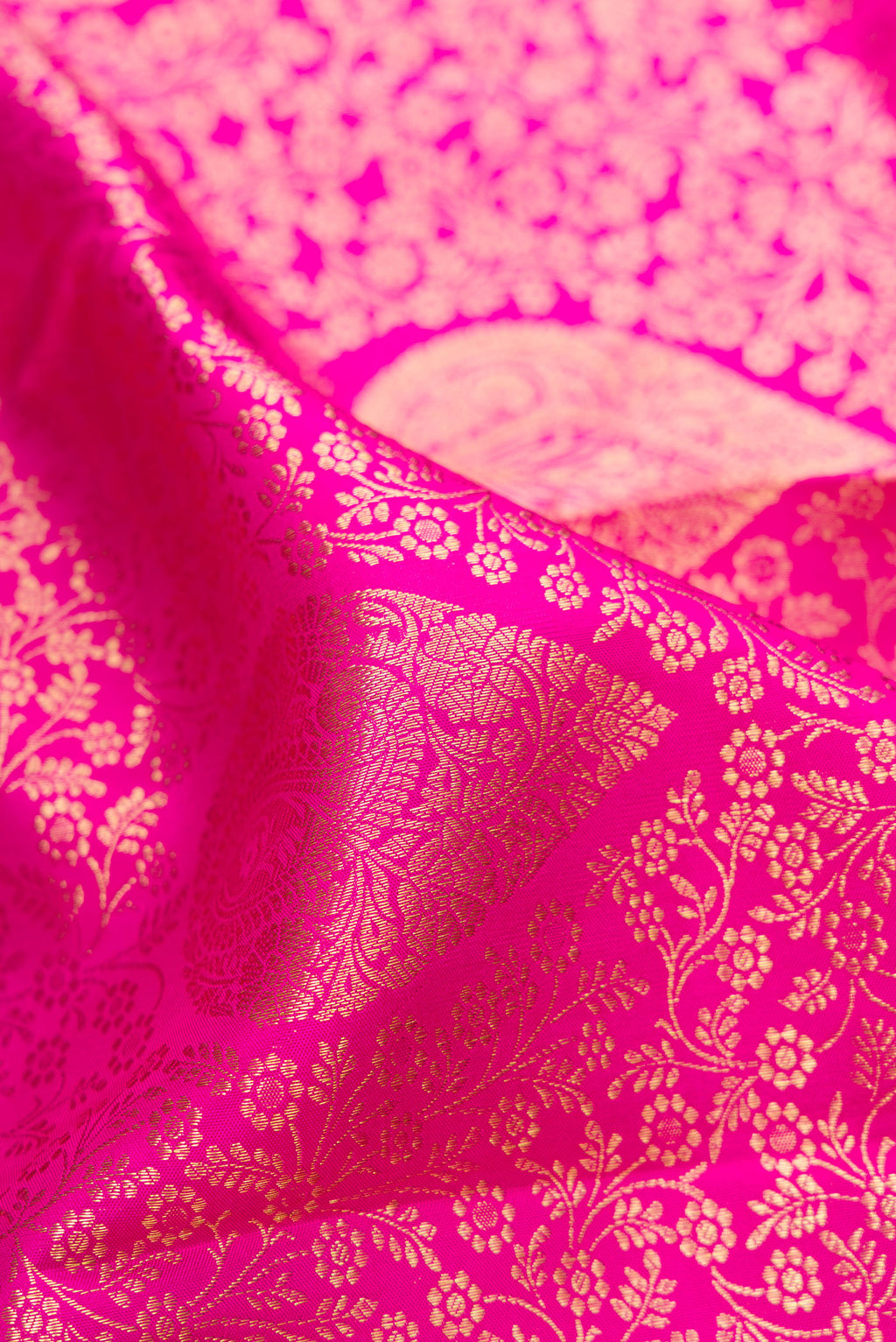 Close up of Rani Pink Kanchipuram Silk Saree with Zari Brocade on the body and Zari Border.  displaying folds