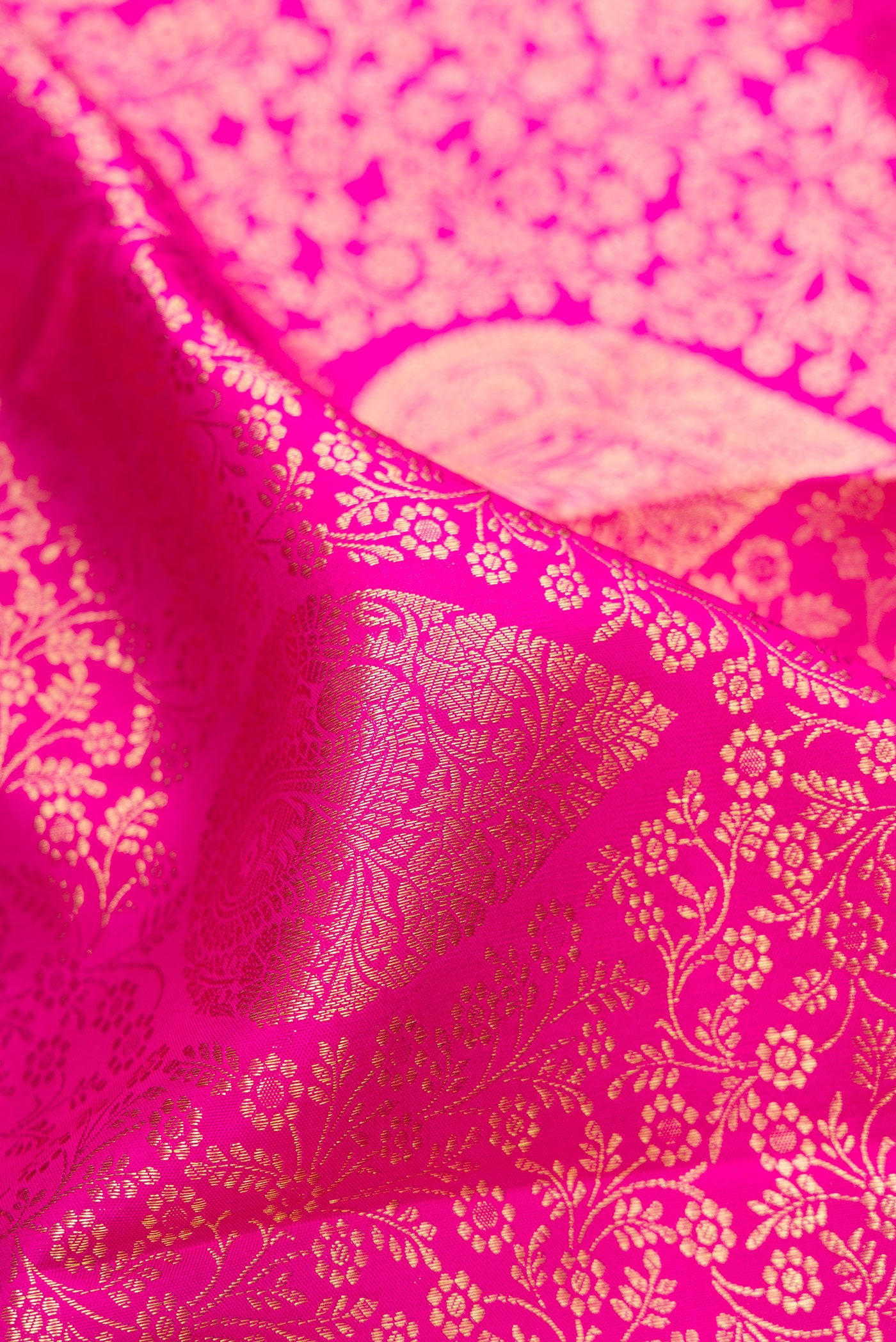 Close up of Rani Pink Kanchipuram Silk Saree with Zari Brocade on the body and Zari Border.  displaying folds