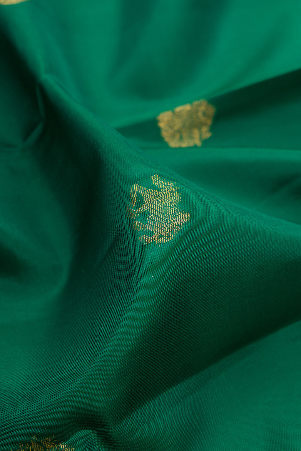 Close up of Green Kanjivaram Silk Saree with Zari Butta on the body and Zari Border.  displaying folds
