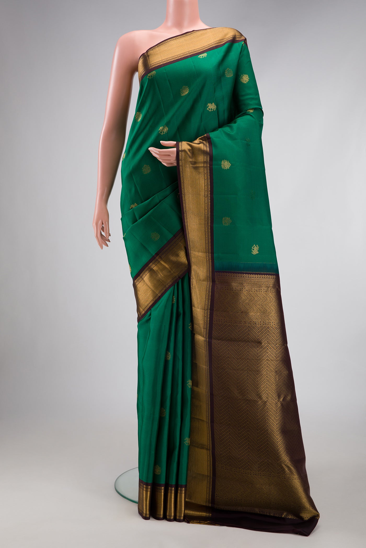 Green Kanjivaram Silk Saree with Zari Butta on the body and Zari Border.  displayed on a mannequin