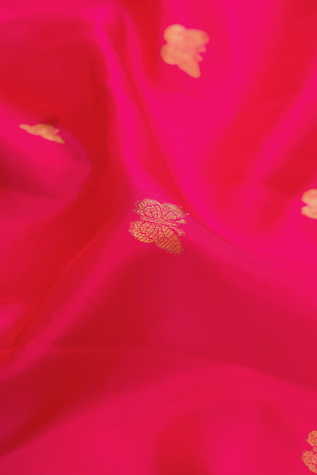 Close up of Dark Pink Kanjivaram Silk Saree with Zari Butta on the body and Zari Border.  displaying folds