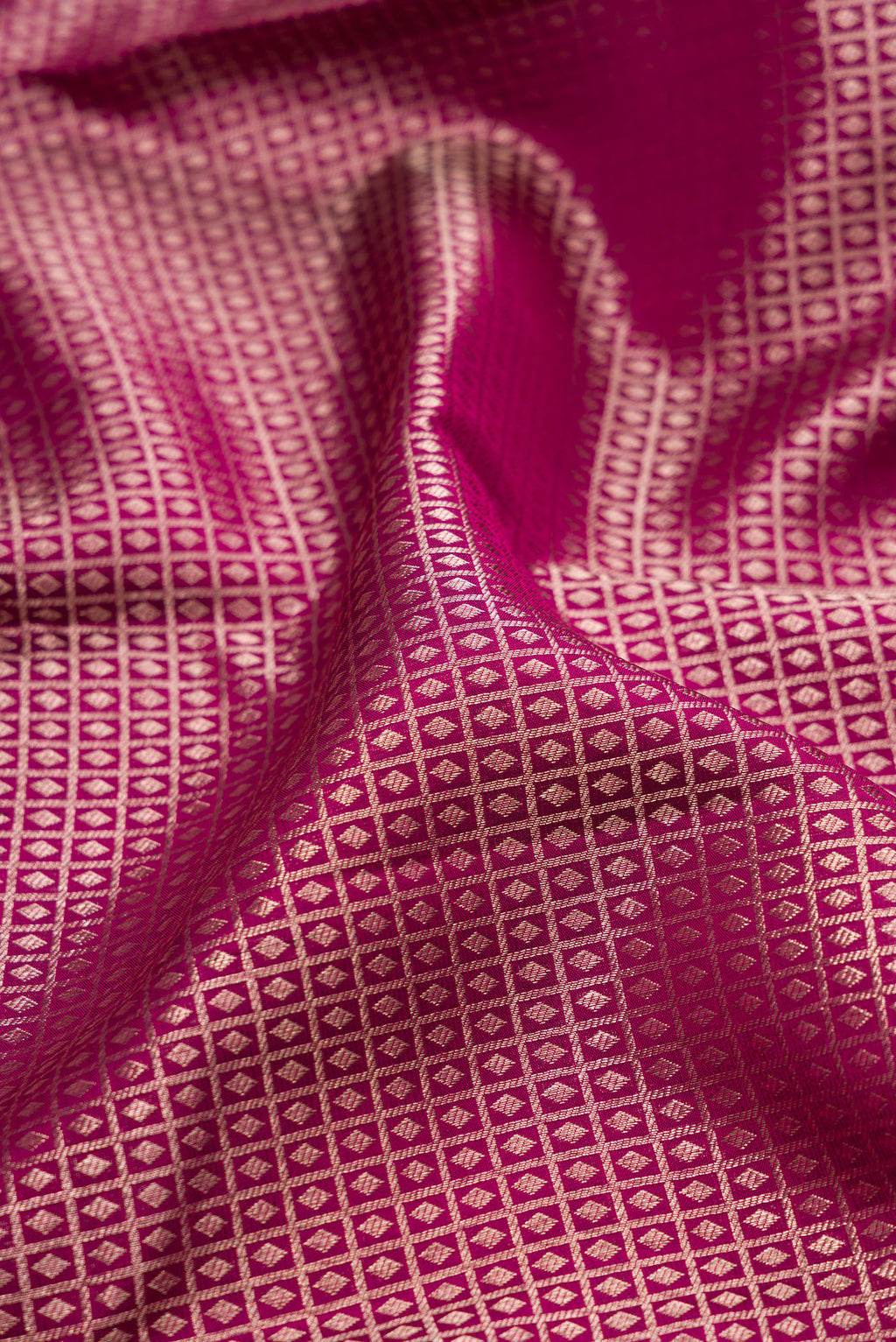 Close up of Magenta Kanchipuram Silk Saree with Zari Brocade on the body and Zari Border.  displaying folds