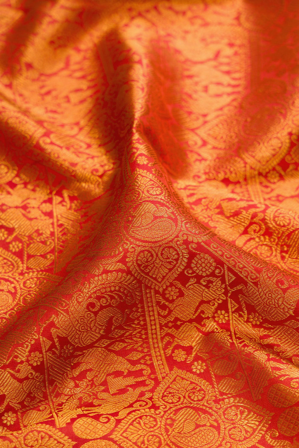Close up of Brick Orange Dual Tone Kanchipuram Silk Saree with Zari Brocade on the body and Zari And Thread Border.  displaying folds