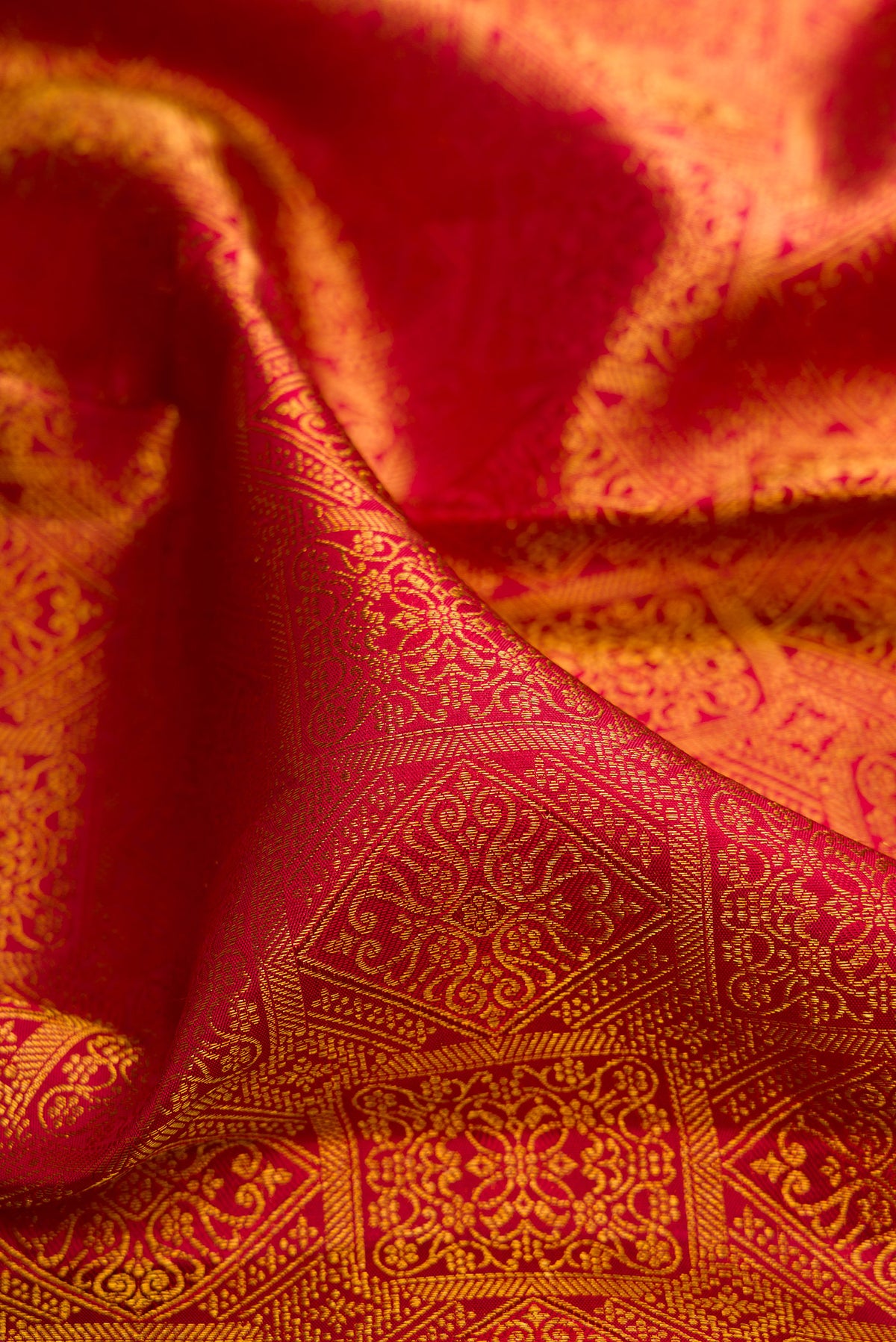Close up of Pure Silk Red Kanchipuram Saree with Zari Brocade on the body and Zari Border.  displaying folds