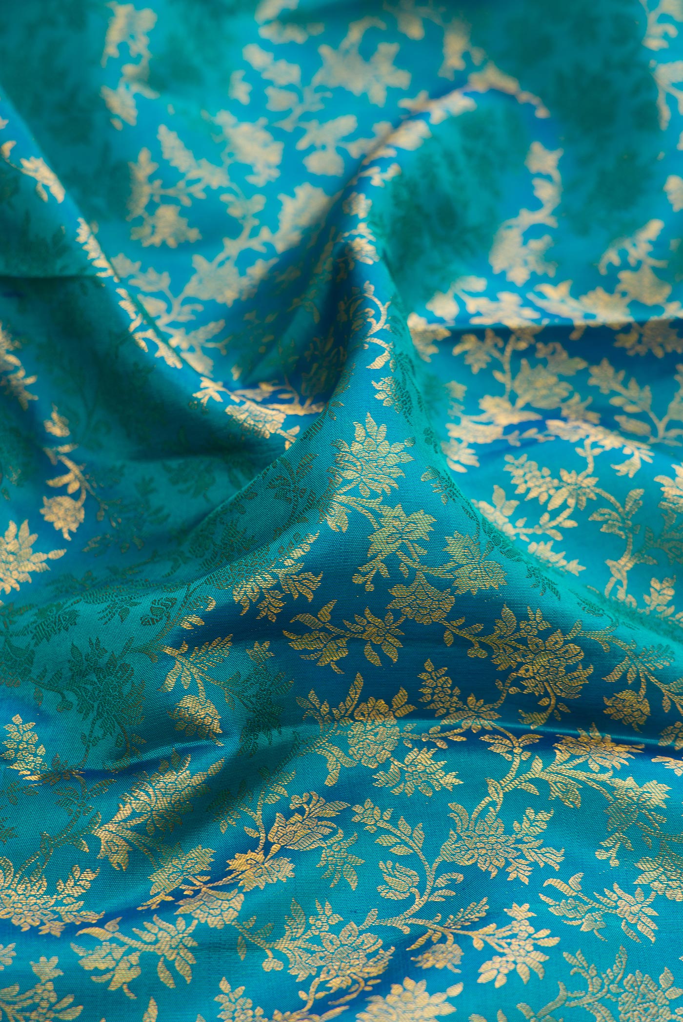 Close up of Teal Kanchipuram Silk Saree with Zari Brocade on the body and Zari Border.  displaying folds