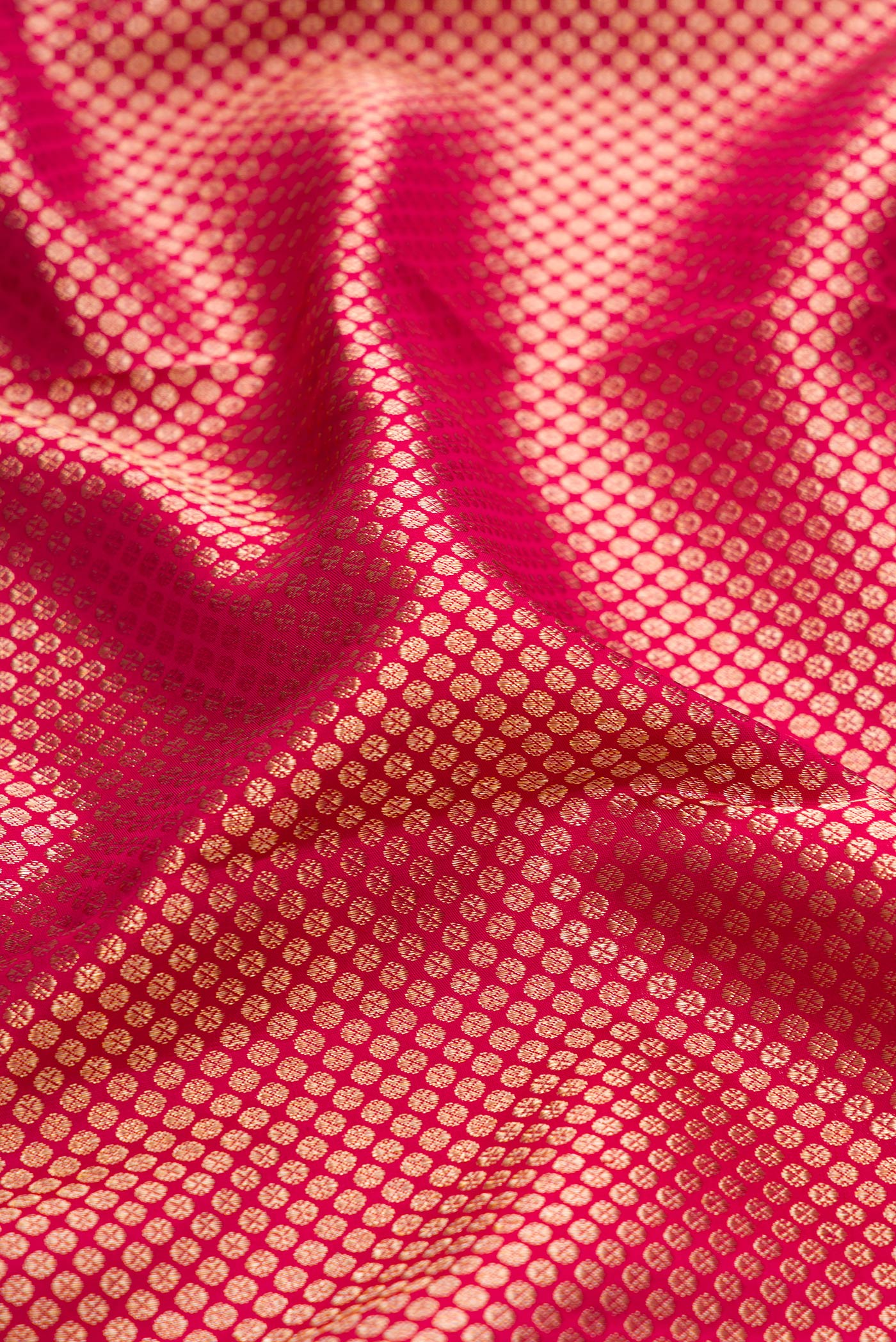 Close up of Rani Pink Kanchipuram Silk Saree with Zari Brocade on the body and Zari Border.  displaying folds
