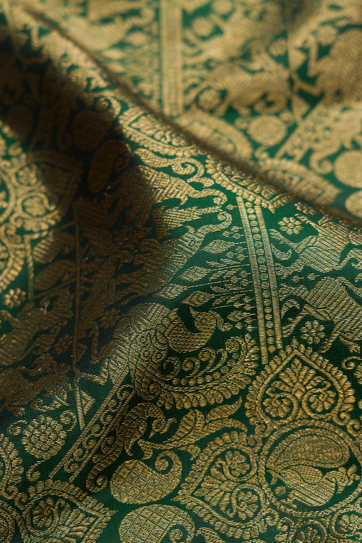 Close up of Bottle Green Kanjivaram Silk Saree with Zari Brocade on the body and Zari Border.  displaying folds