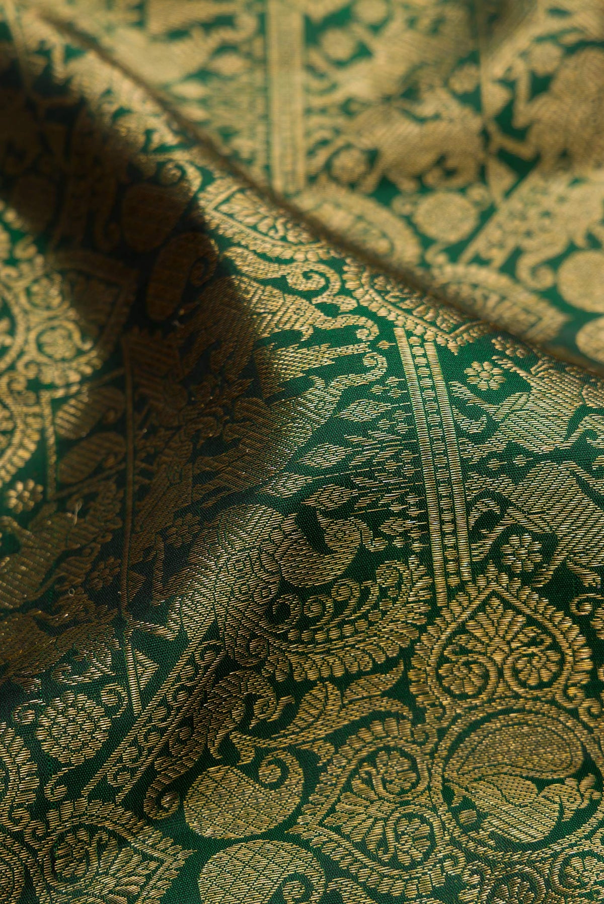 Close up of Bottle Green Kanjivaram Silk Saree with Zari Brocade on the body and Zari Border.  displaying folds