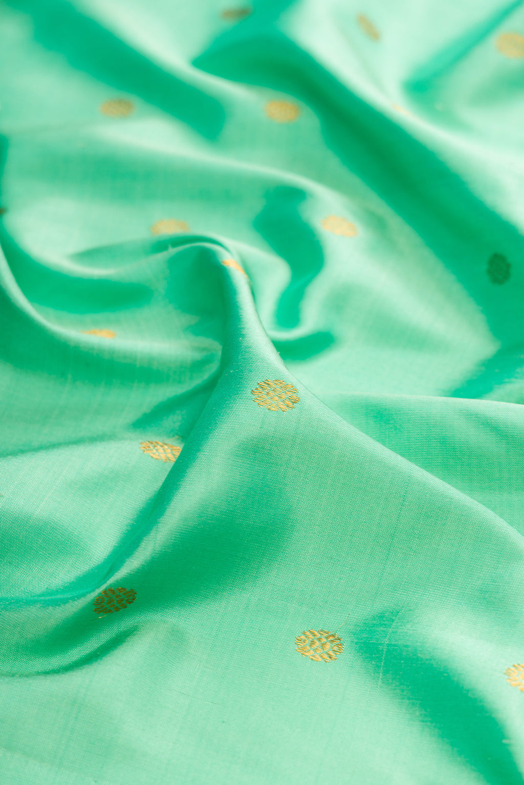 Close up of Sea Green Gadwal Silk Saree with Zari Butta on the body and Zari Border.  displaying folds