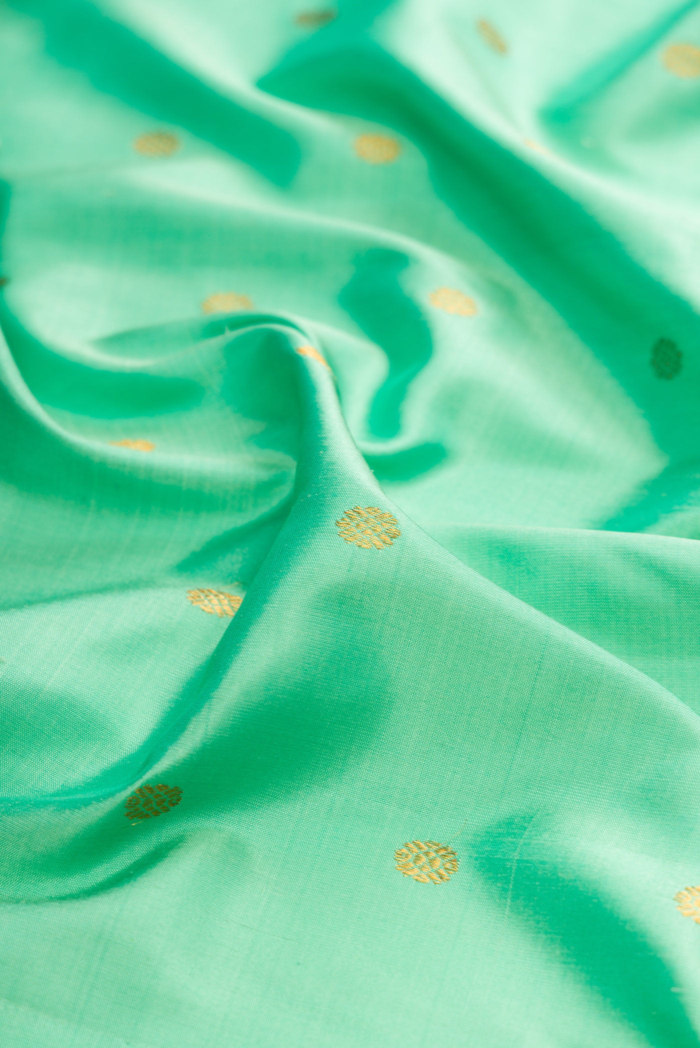 Close up of Sea Green Gadwal Silk Saree with Zari Butta on the body and Zari Border.  displaying folds