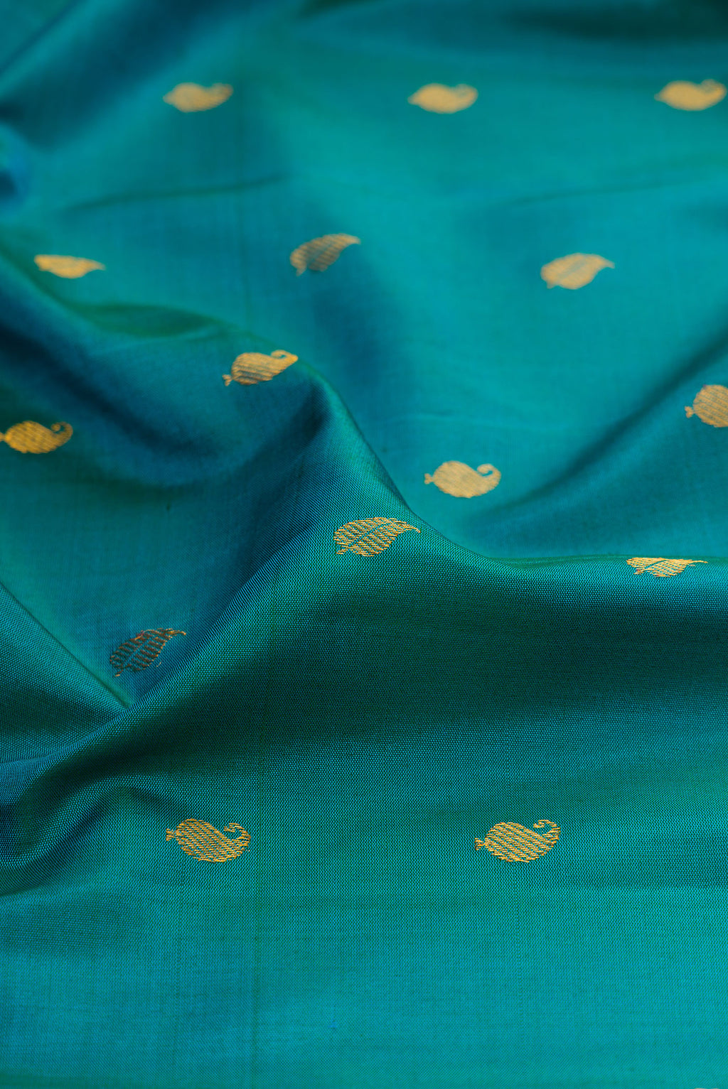 Close up of Peacock Blue Gadwal Silk Saree with Zari Butta on the body and Zari Border.  displaying folds