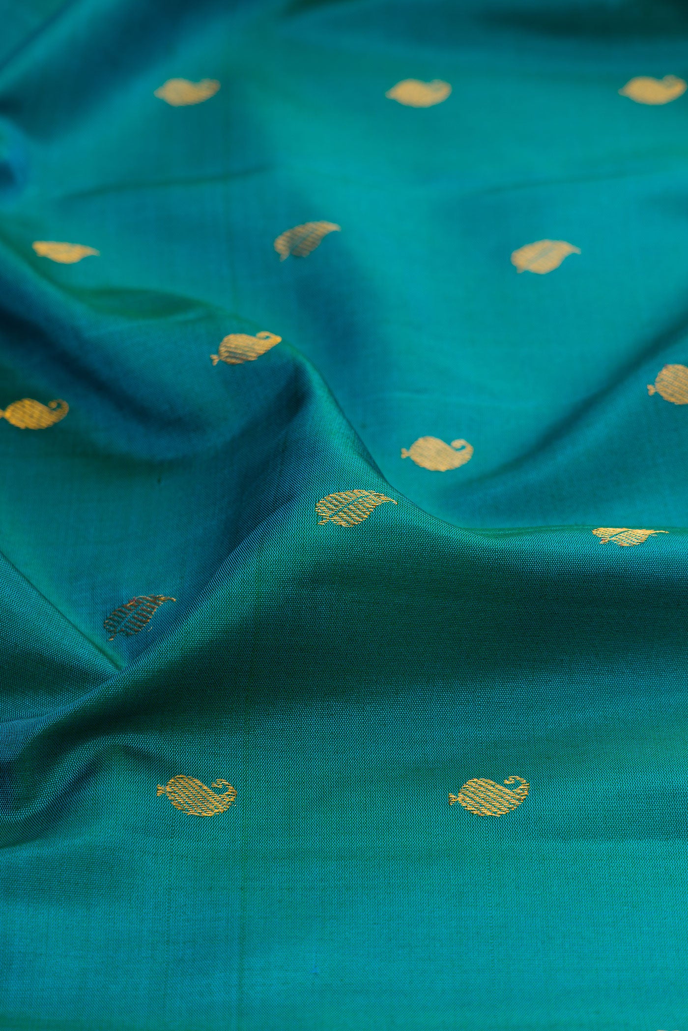 Close up of Peacock Blue Gadwal Silk Saree with Zari Butta on the body and Zari Border.  displaying folds