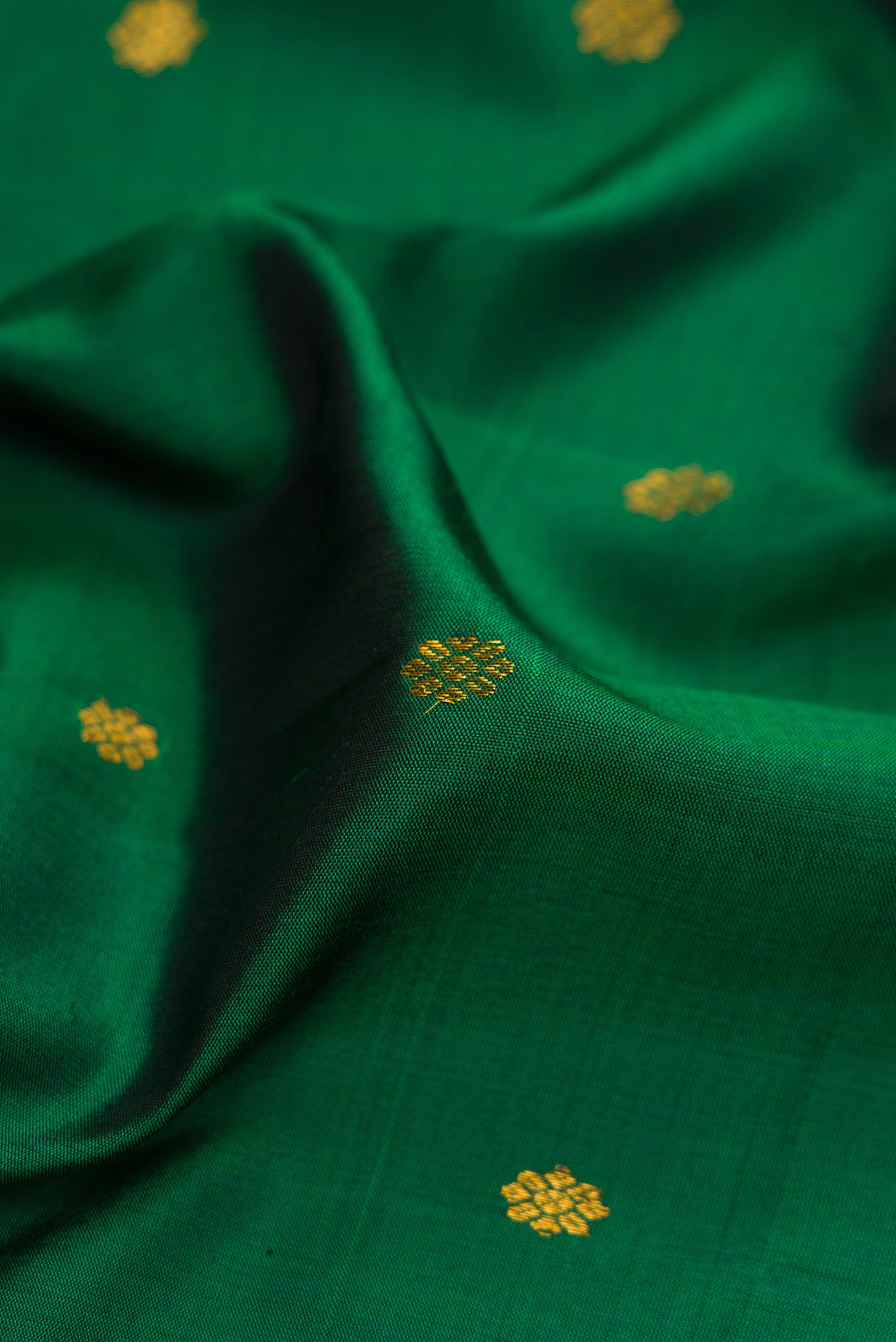Close up of Bottle Green Gadwal Silk Saree with Zari Butta on the body and Temple Border.  displaying folds