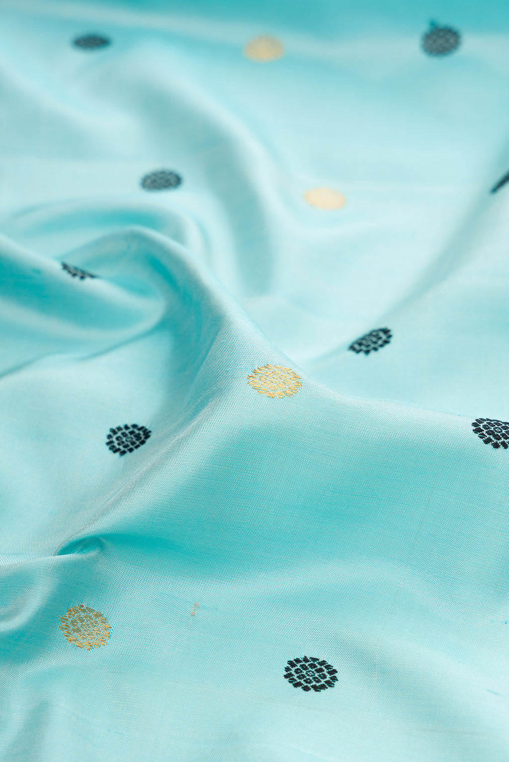 Close up of Sky Blue Gadwal Silk Saree with Zari And Thread Butta on the body and Temple Border.  displaying folds