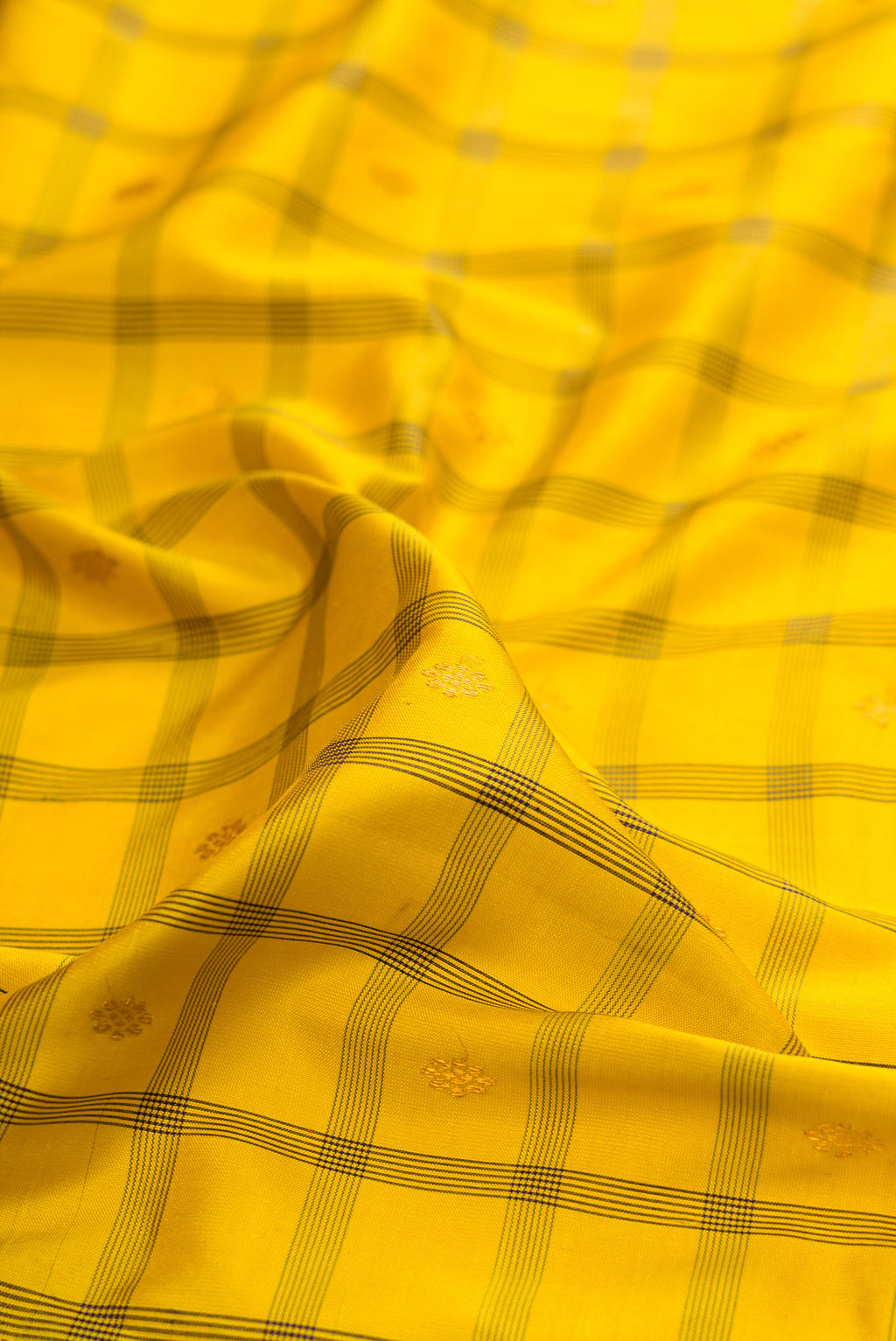 Close up of Yellow Gadwal Silk Saree with Checked design on the body and Temple Border.  displaying folds