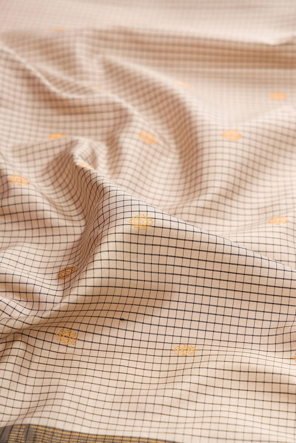 Close up of Beige Gadwal Silk Saree with Checked design on the body and Temple Border.  displaying folds
