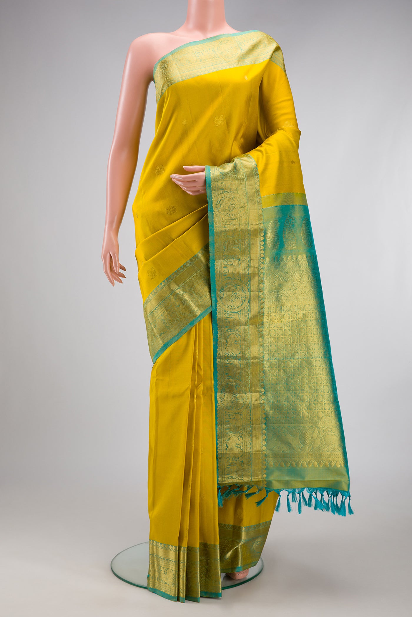Yellow Gadwal Silk Saree with Zari Butta on the body and Temple Border.  displayed on a mannequin