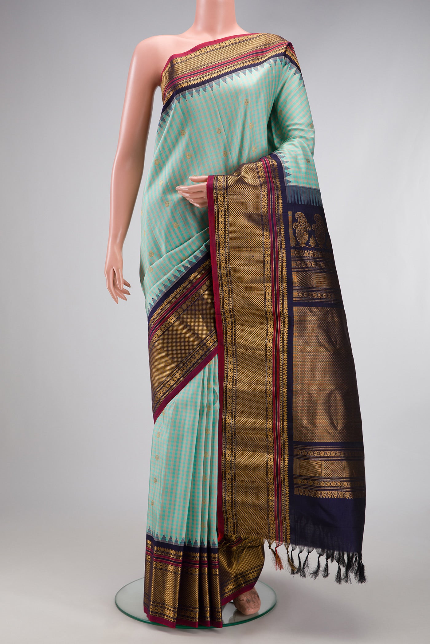 Light Blue Gadwal Silk Saree with Checked design on the body and Temple Border.  displayed on a mannequin