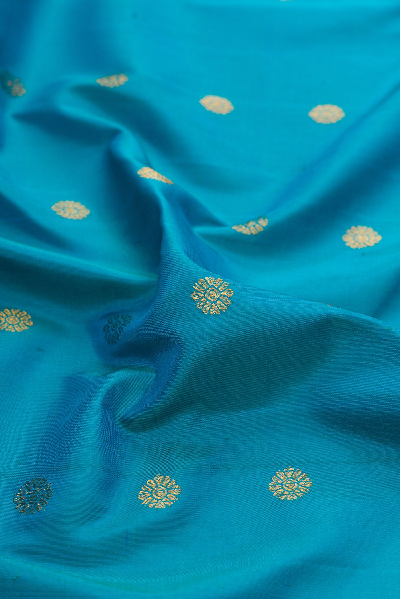 Close up of Peacock Blue Paithani Silk Saree with Zari Butta on the body and Paithani Border.  displaying folds
