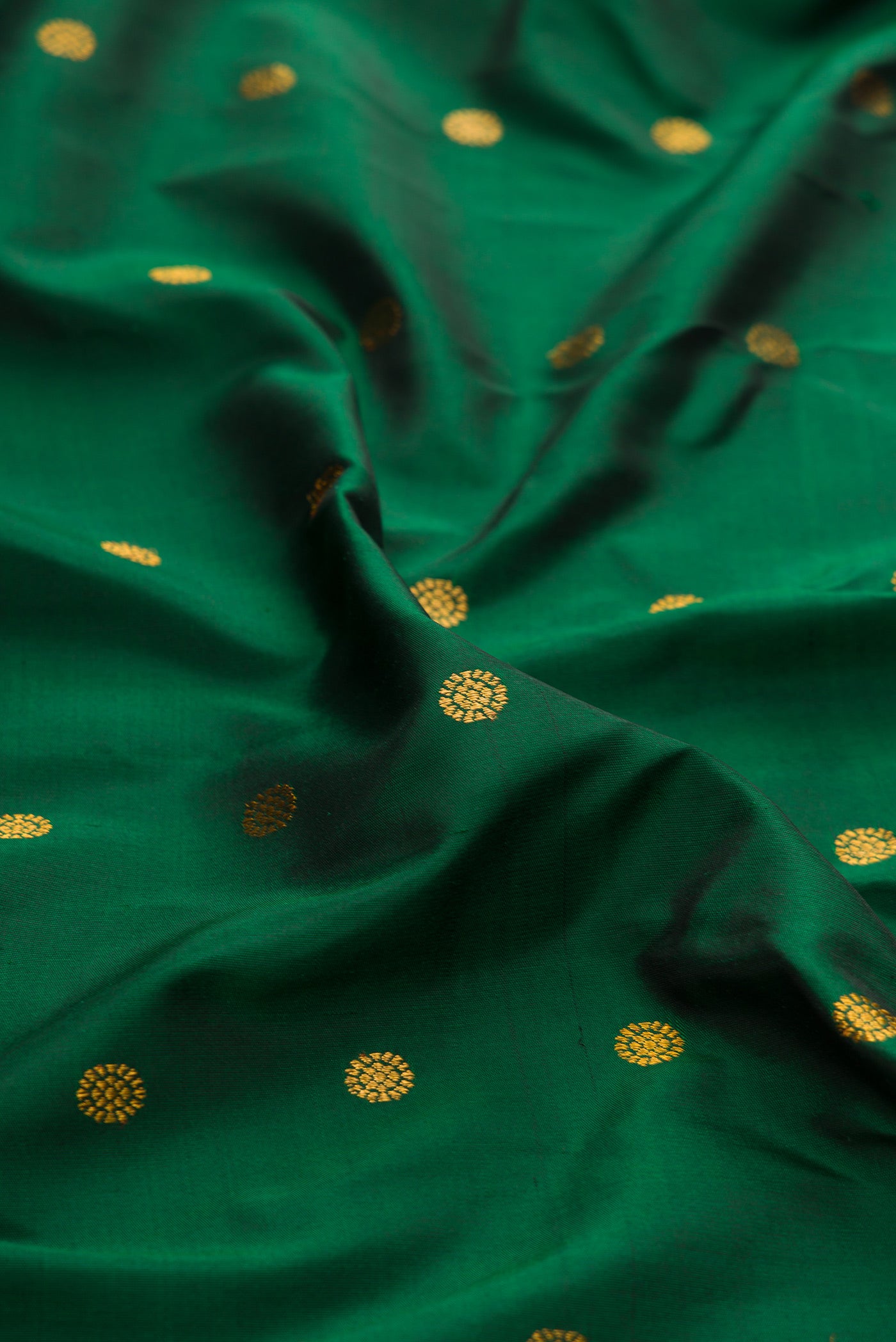 Close up of Bottle Green Paithani Silk Saree with Zari Butta on the body and Paithani Border.  displaying folds