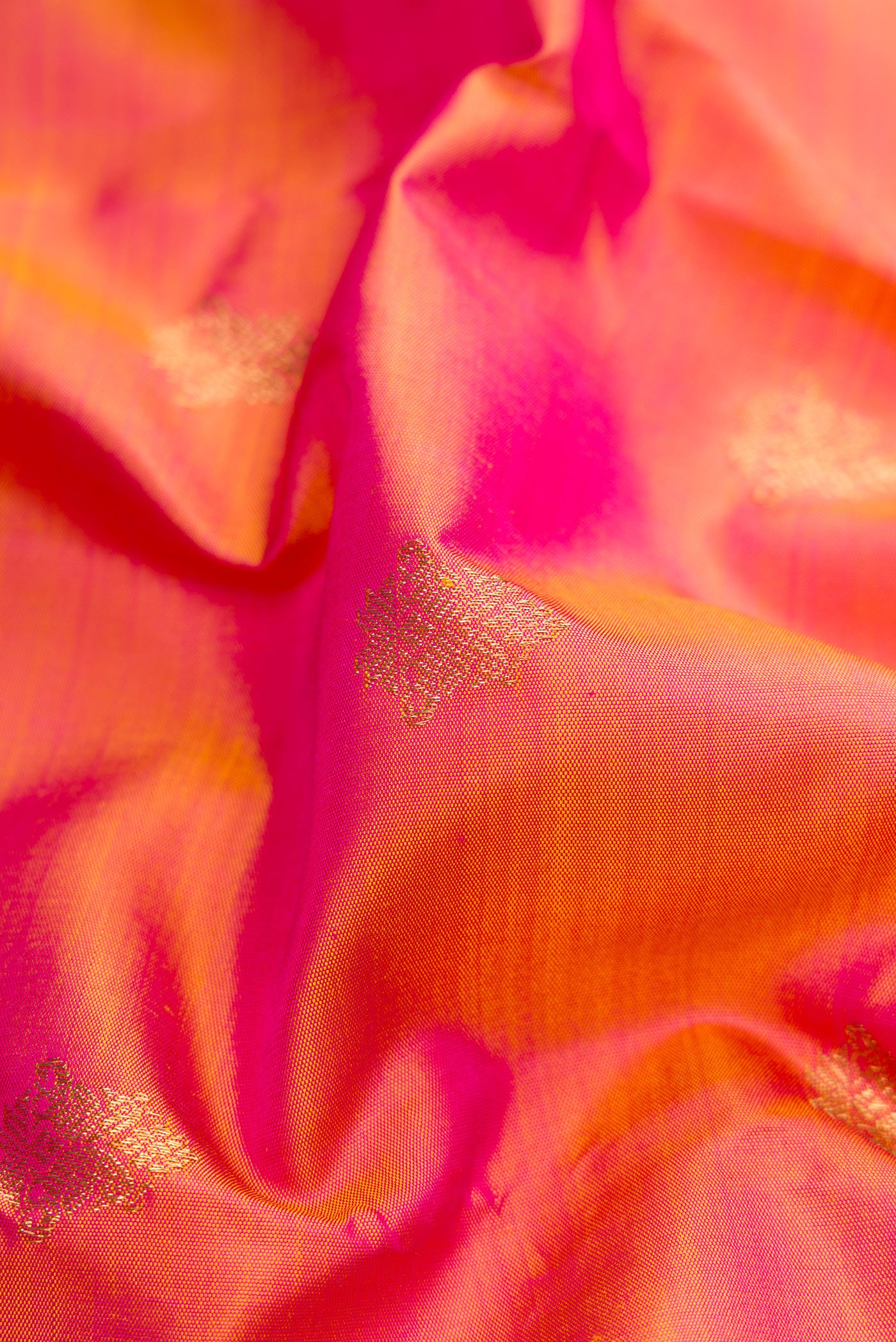 Close up of Pure Silk Pure Zari Coral Dual Tone Kanjivaram Saree with Zari Butta on the body and Zari Border.  displaying folds