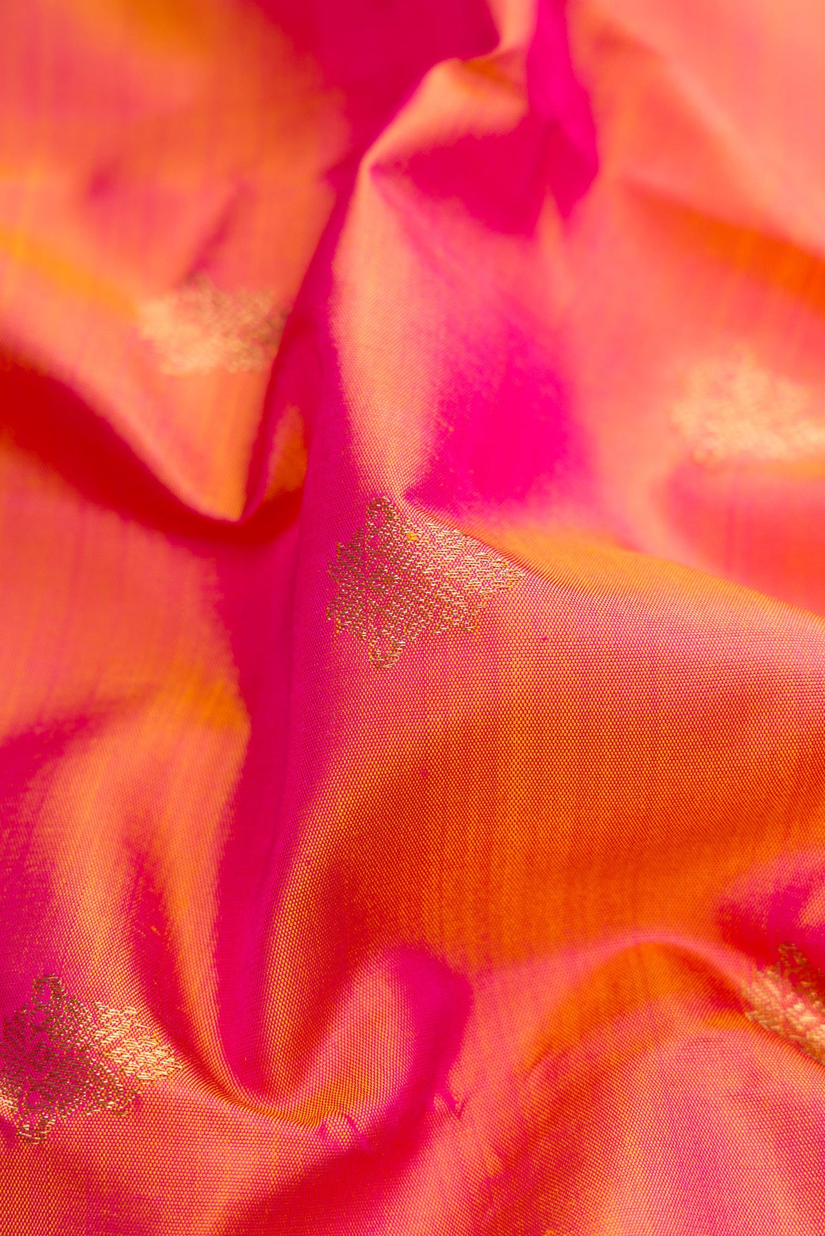 Close up of Pure Silk Pure Zari Coral Dual Tone Kanjivaram Saree with Zari Butta on the body and Zari Border.  displaying folds