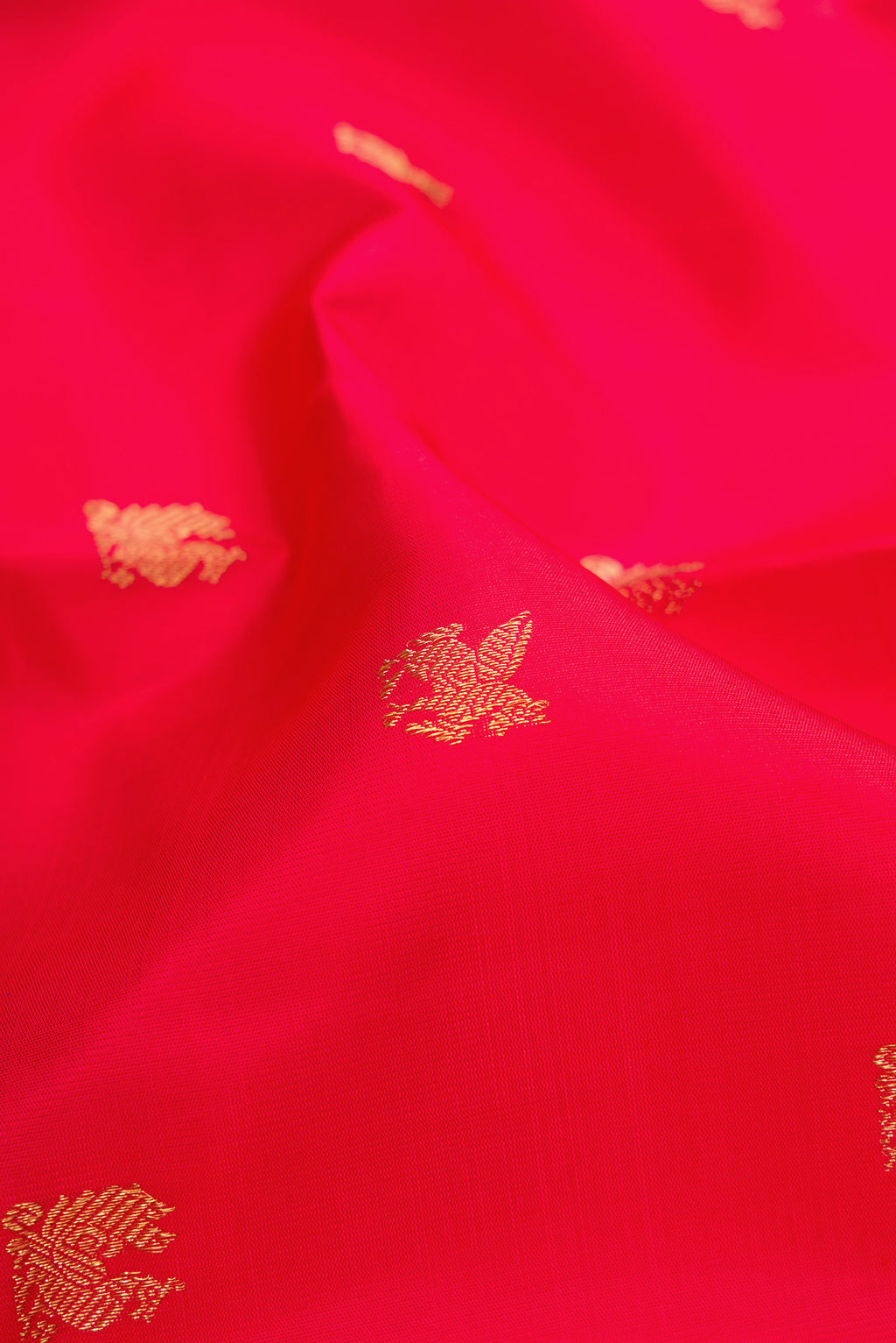 Close up of Pure Silk Pure Zari Red Dual Tone Kanjivaram Saree with Zari Butta on the body and Zari Border.  displaying folds