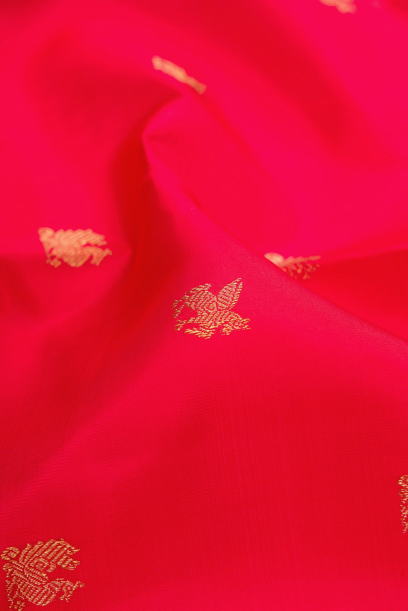 Close up of Pure Silk Pure Zari Red Dual Tone Kanjivaram Saree with Zari Butta on the body and Zari Border.  displaying folds