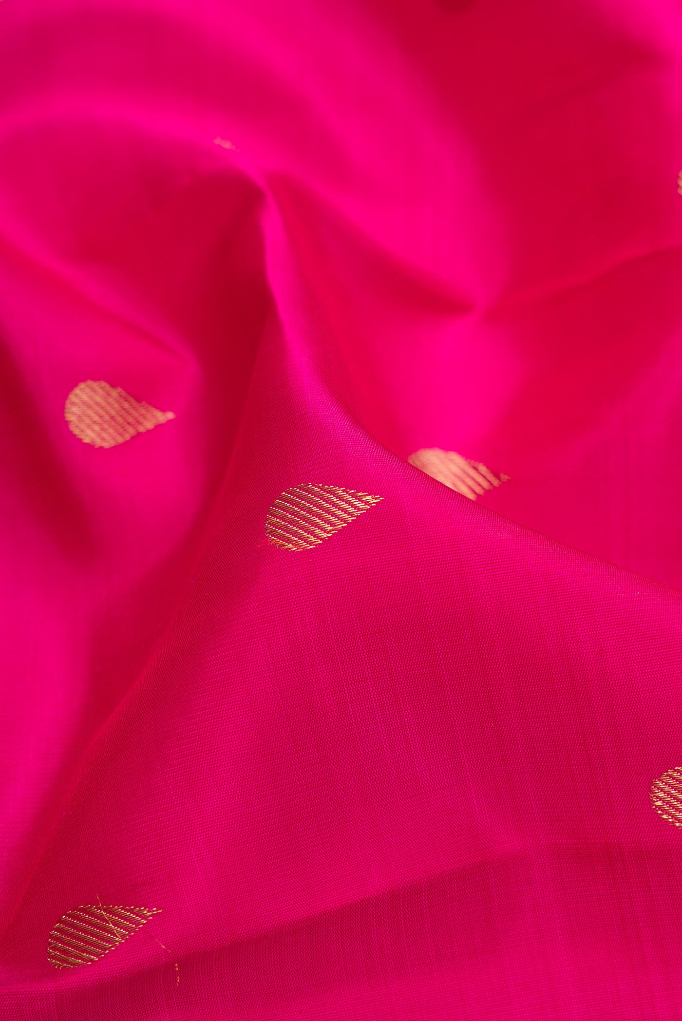 Close up of Pure Silk Pure Zari Dark Pink Kanjivaram Saree with Zari Butta on the body and Zari Border.  displaying folds