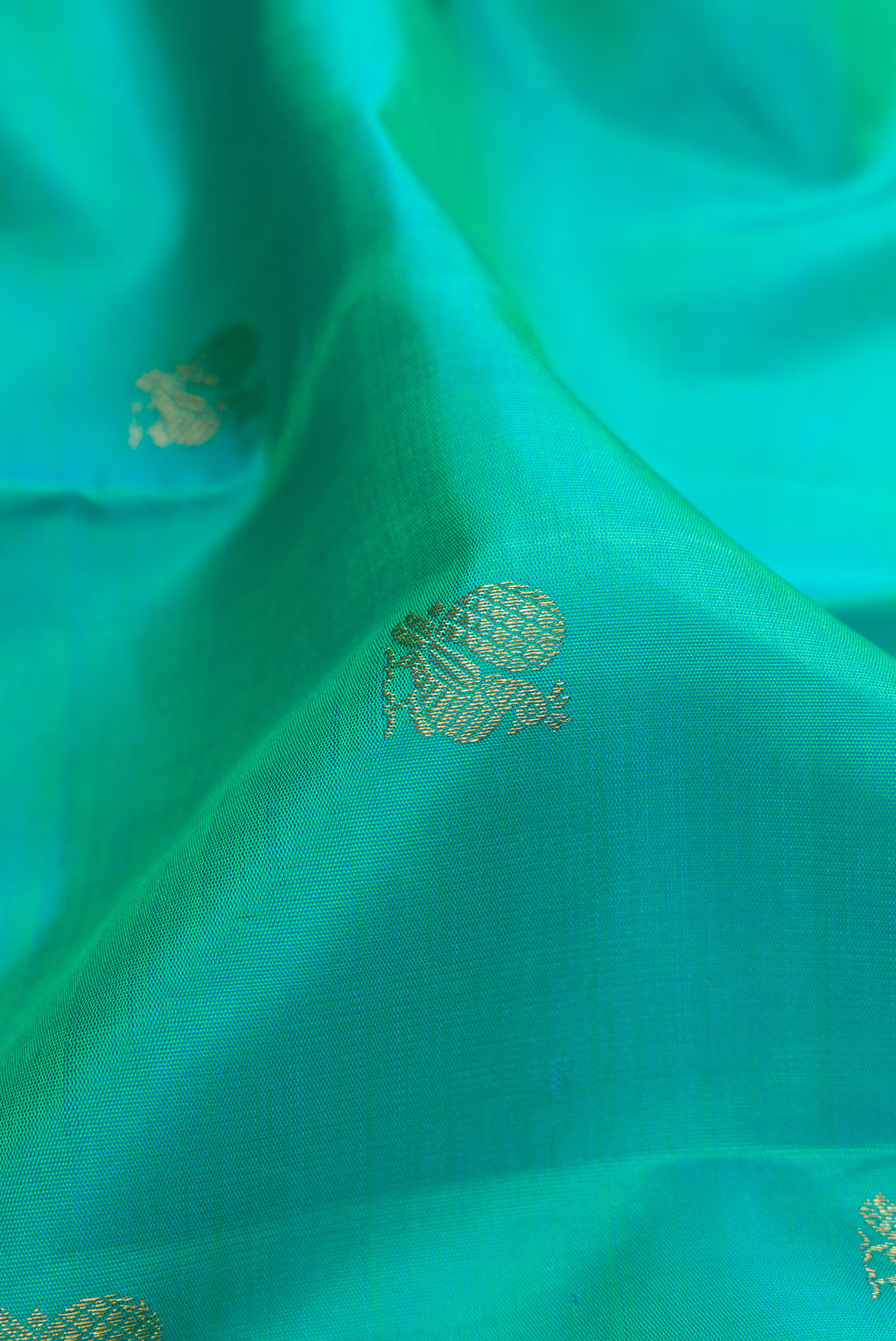 Close up of Pure Silk Pure Zari Turquoise Kanjivaram Saree with Zari Butta on the body and Zari Border.  displaying folds