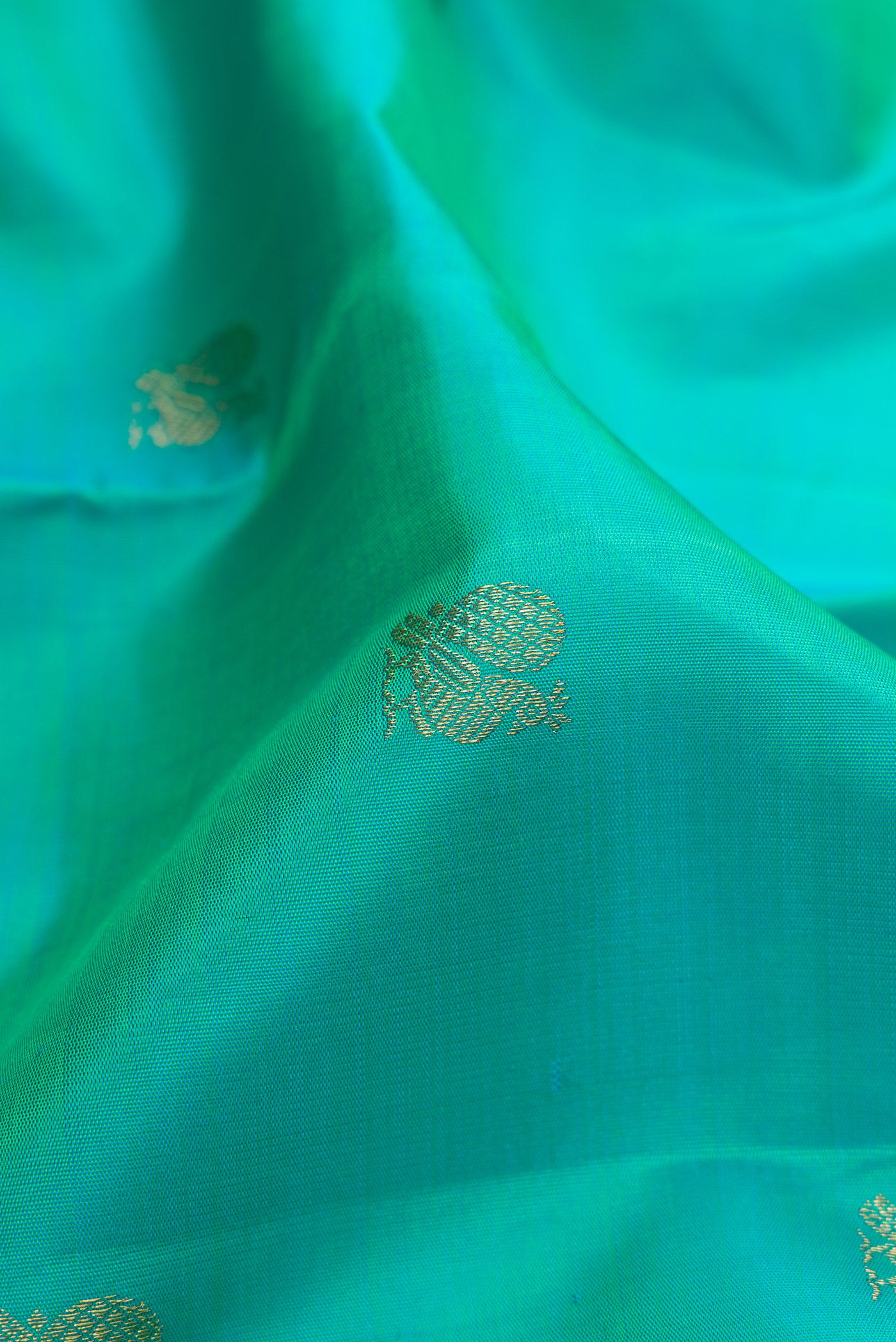Close up of Pure Silk Pure Zari Turquoise Kanjivaram Saree with Zari Butta on the body and Zari Border.  displaying folds
