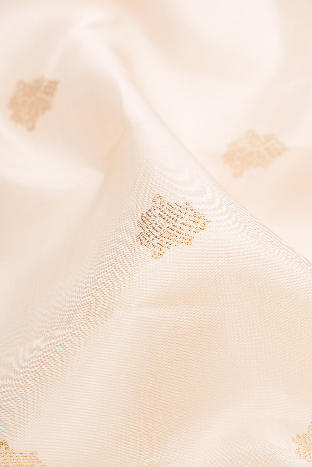 Close up of Pure Silk Pure Zari Off White Kanjivaram Saree with Zari Butta on the body and Zari Border.  displaying folds