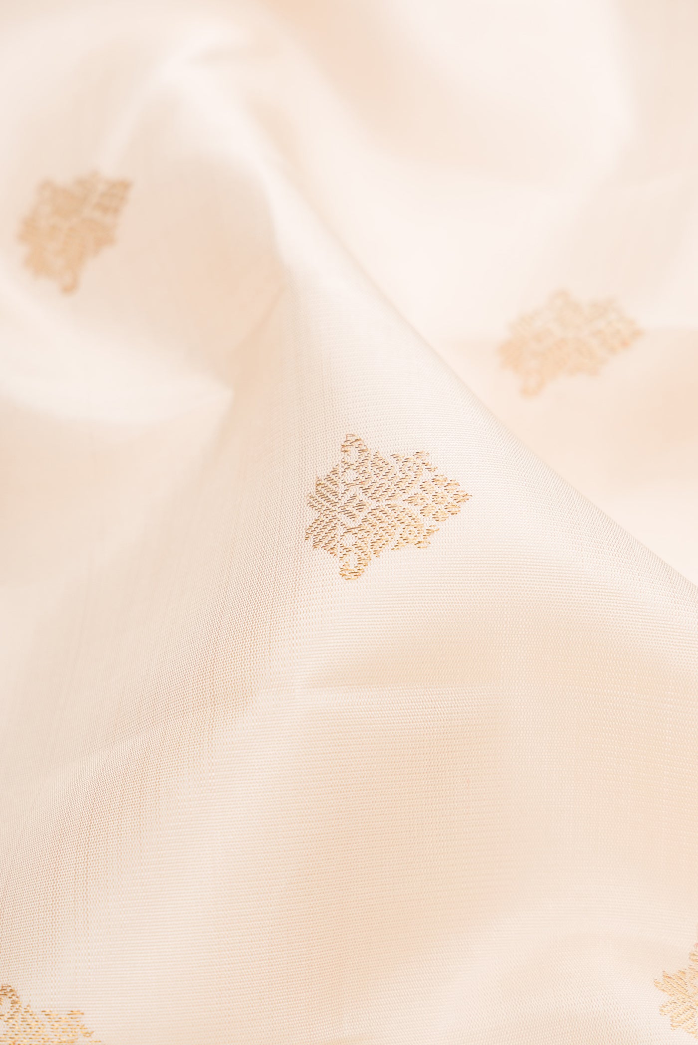 Close up of Pure Silk Pure Zari Off White Kanjivaram Saree with Zari Butta on the body and Zari Border.  displaying folds