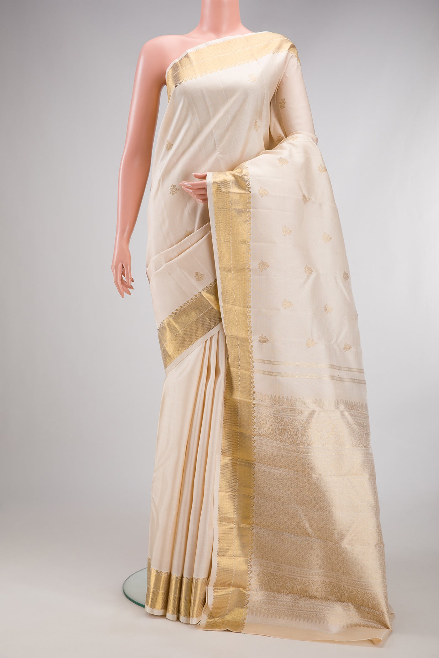 Pure Silk Pure Zari Off White Kanjivaram Saree with Zari Butta on the body and Zari Border.  displayed on a mannequin