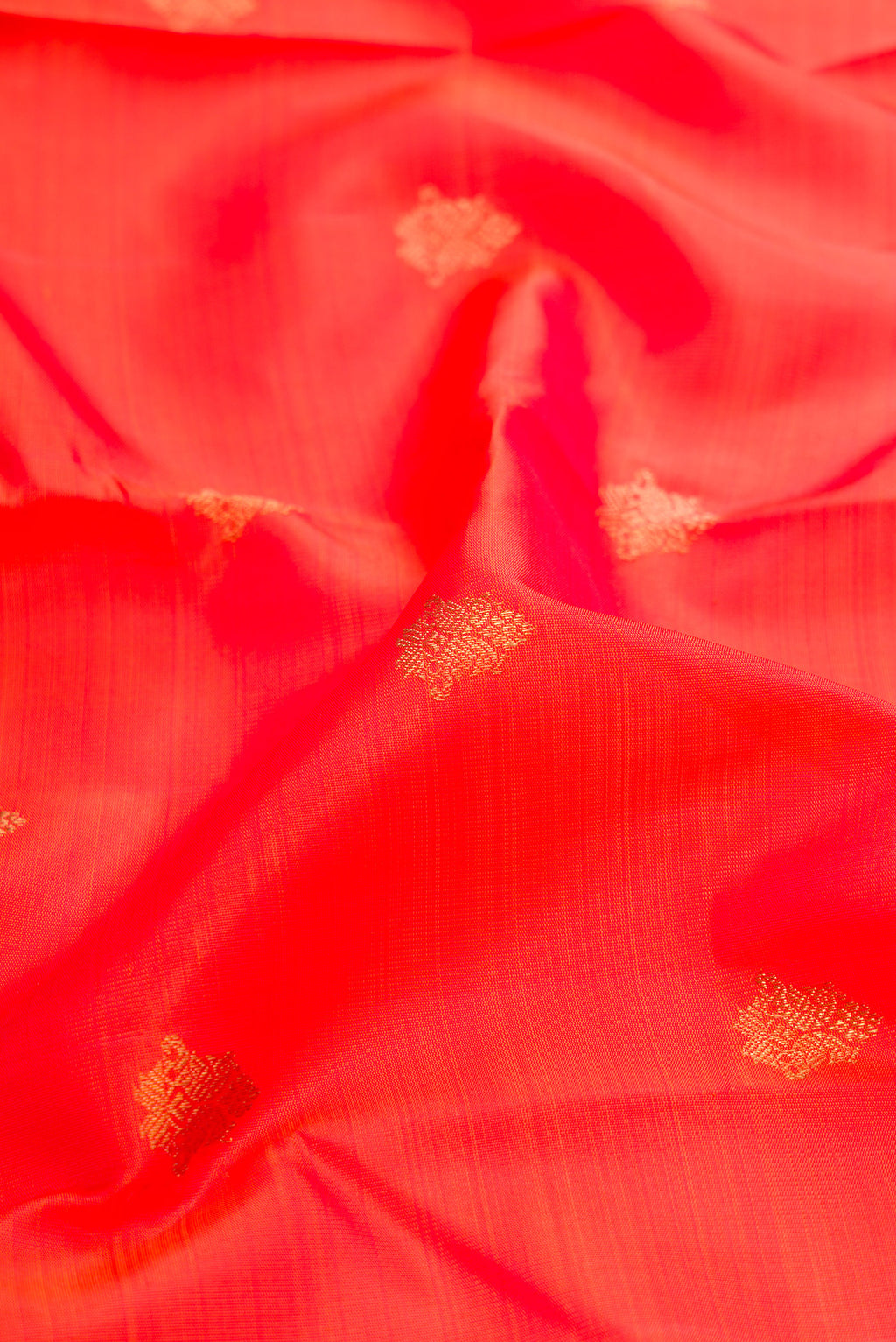 Close up of Pure Silk Pure Zari Orange Dual Tone Kanjivaram Saree with Zari Butta on the body and Zari Border.  displaying folds