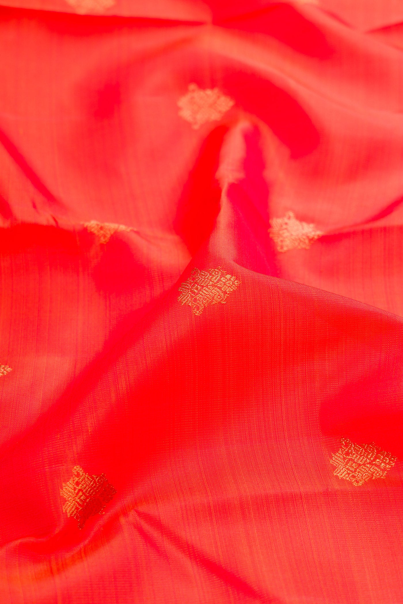 Close up of Pure Silk Pure Zari Orange Dual Tone Kanjivaram Saree with Zari Butta on the body and Zari Border.  displaying folds