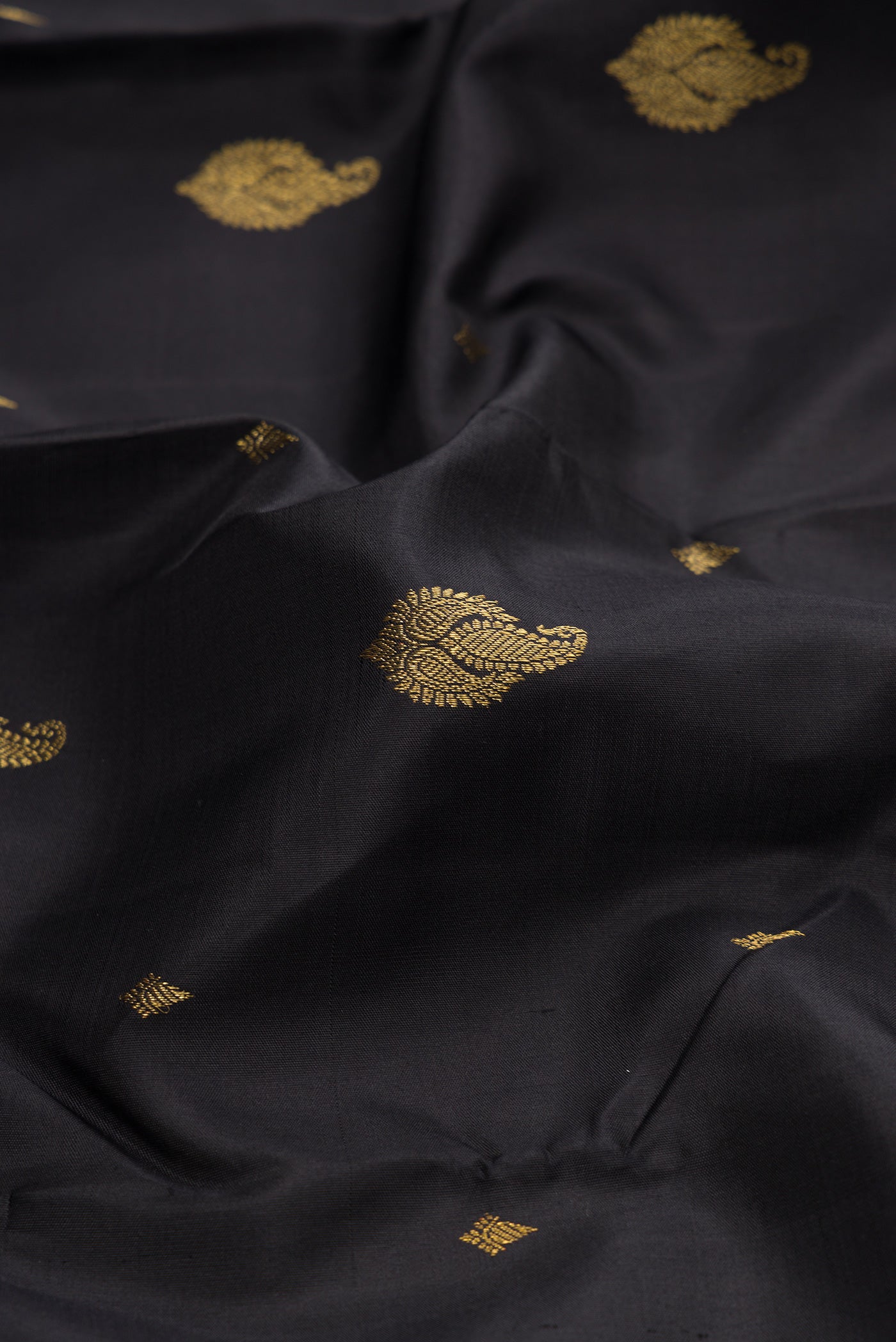 Close up of Black Kanchipuram Silk Saree with Zari Butta on the body and Zari Border.  displaying folds